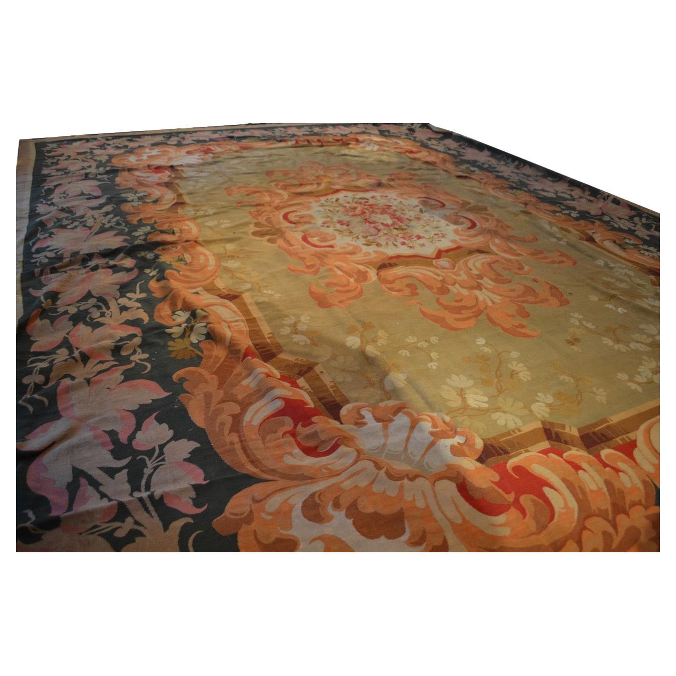 A magnificent Napoleon III Aubusson weave carpet having an unusual colour palette including two outer borders in pinks, reds, dark green, and an inner field in olive green with a central medallion of flowers and swirling borders. The carpet features