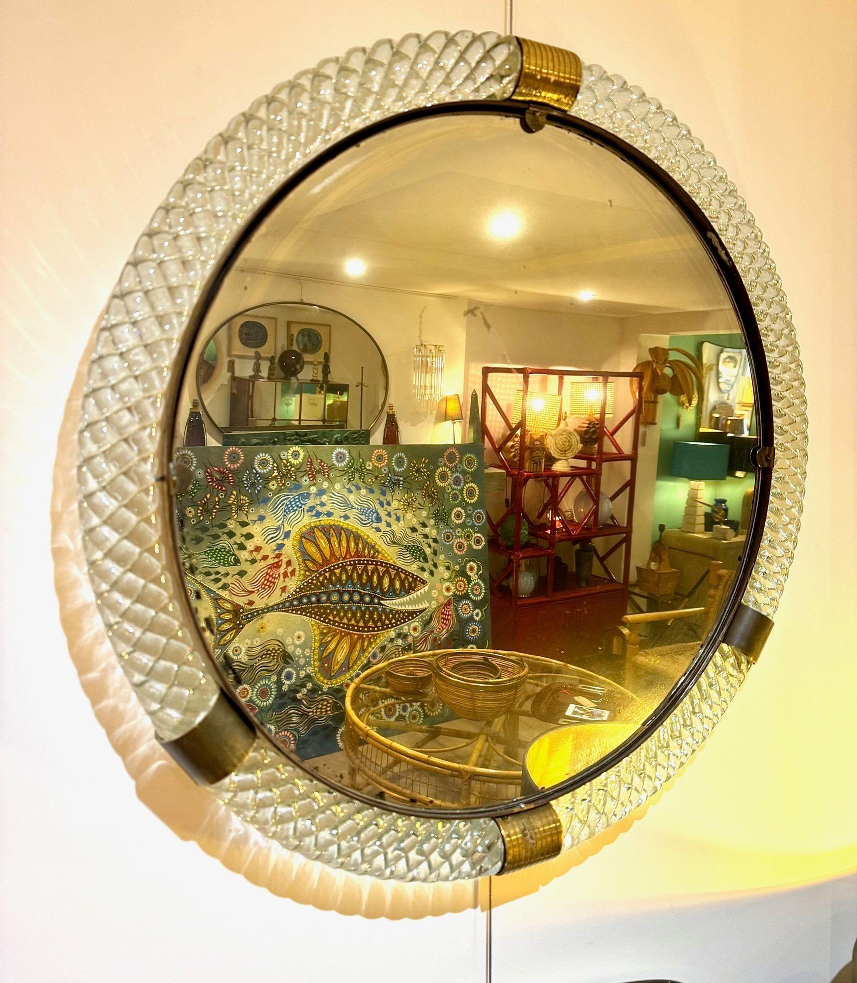 Un maravilloso gran  Espejo circular de Murano Torchon de 1940, de cristal transparente y latón, con placa de espejo original. La placa de espejo presenta algunas marcas en los bordes y en el centro, propias de la edad, que pueden verse en la 10ª