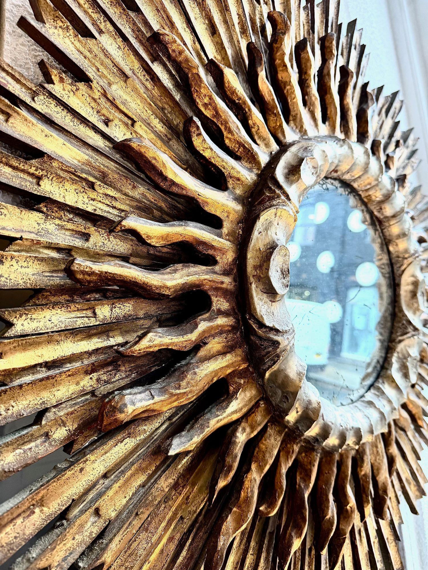 Grande specchio francese degli anni '40 in legno intagliato e dorato, con due strati intagliati con diversi disegni di raggi solari e una cornice circolare centrale rialzata. Con lastra di specchio originale che presenta alcuni segni di foxing ai