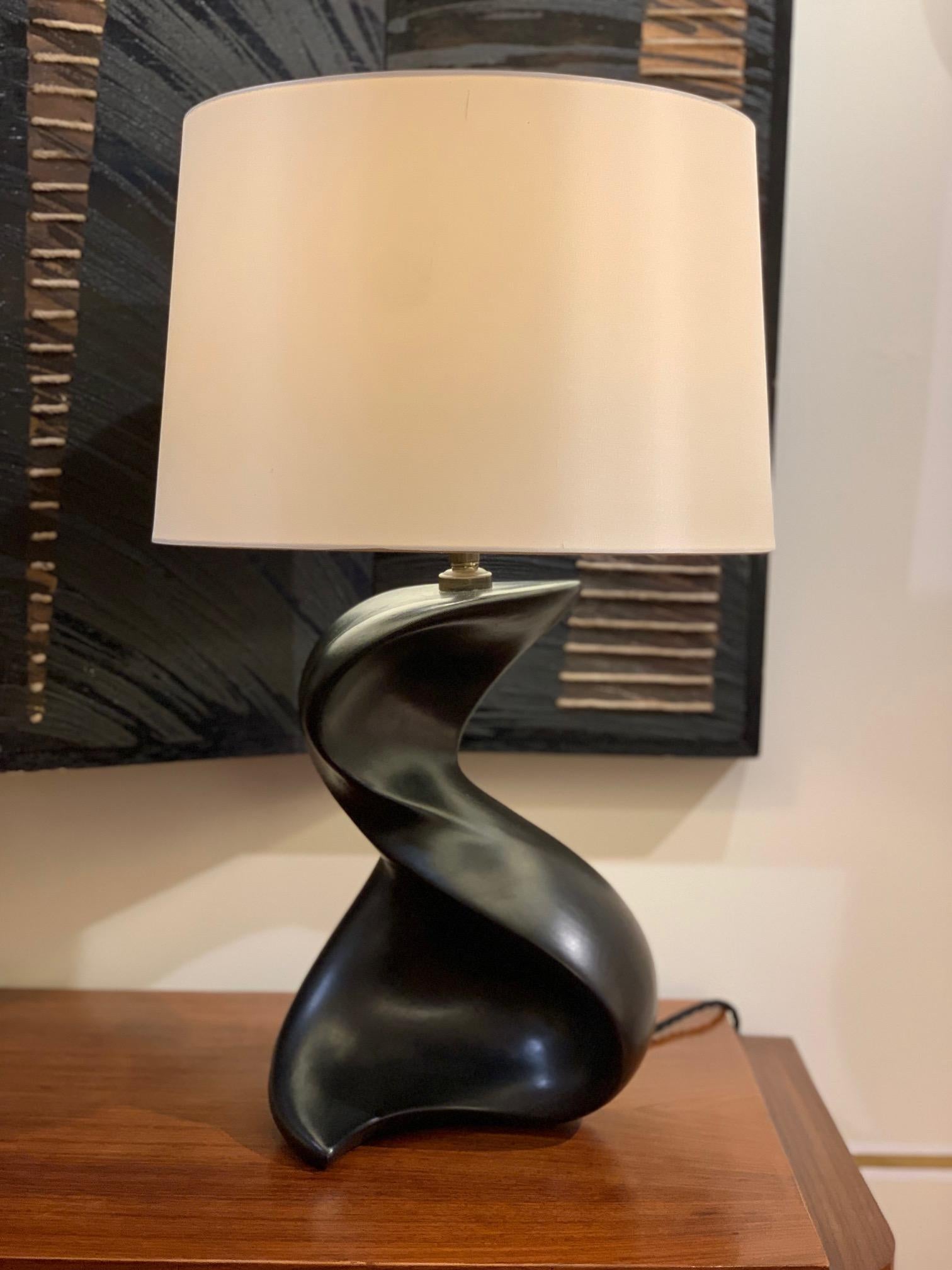 A large freeform black ceramic table lamp, with a distinctive slightly metallic glaze
France, circa 1950
Including the shade: 58 cm high by 35 cm diameter
Base only, ex fitting: 32cm high by 23 cm wide.