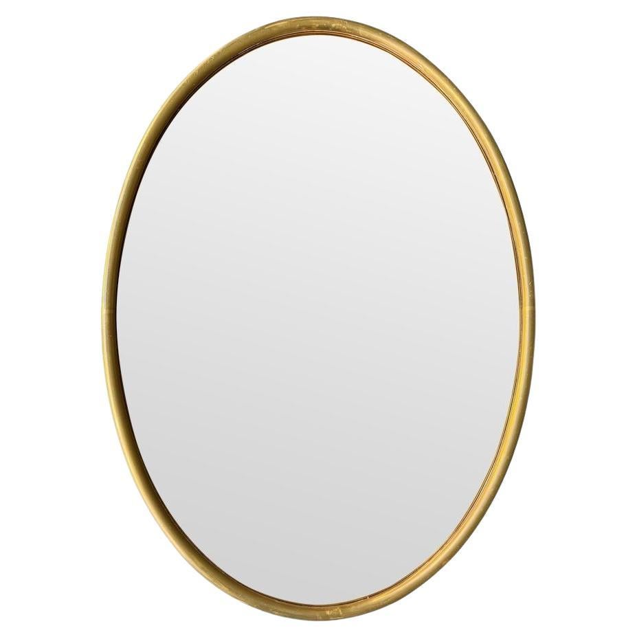 A large 1970s Italian brass framed oval mirror with bronzed mirror plate