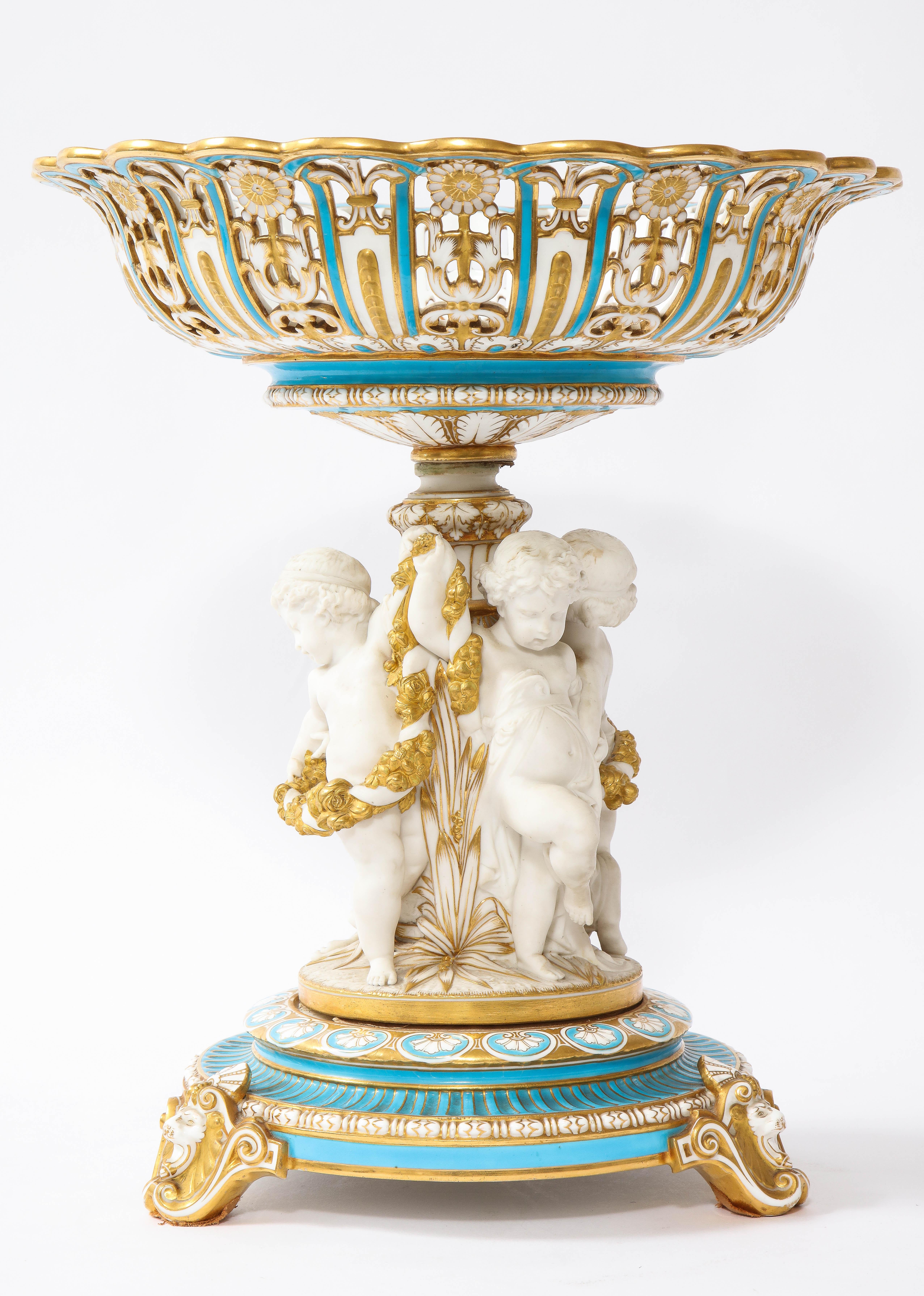 Un grand centre de table en porcelaine Mintons Biscuit anglaise du 19ème siècle avec des Putties dansants.  Ce travail exquis illustre le haut niveau d'artisanat caractéristique de l'époque. La pièce centrale présente à son sommet un panier