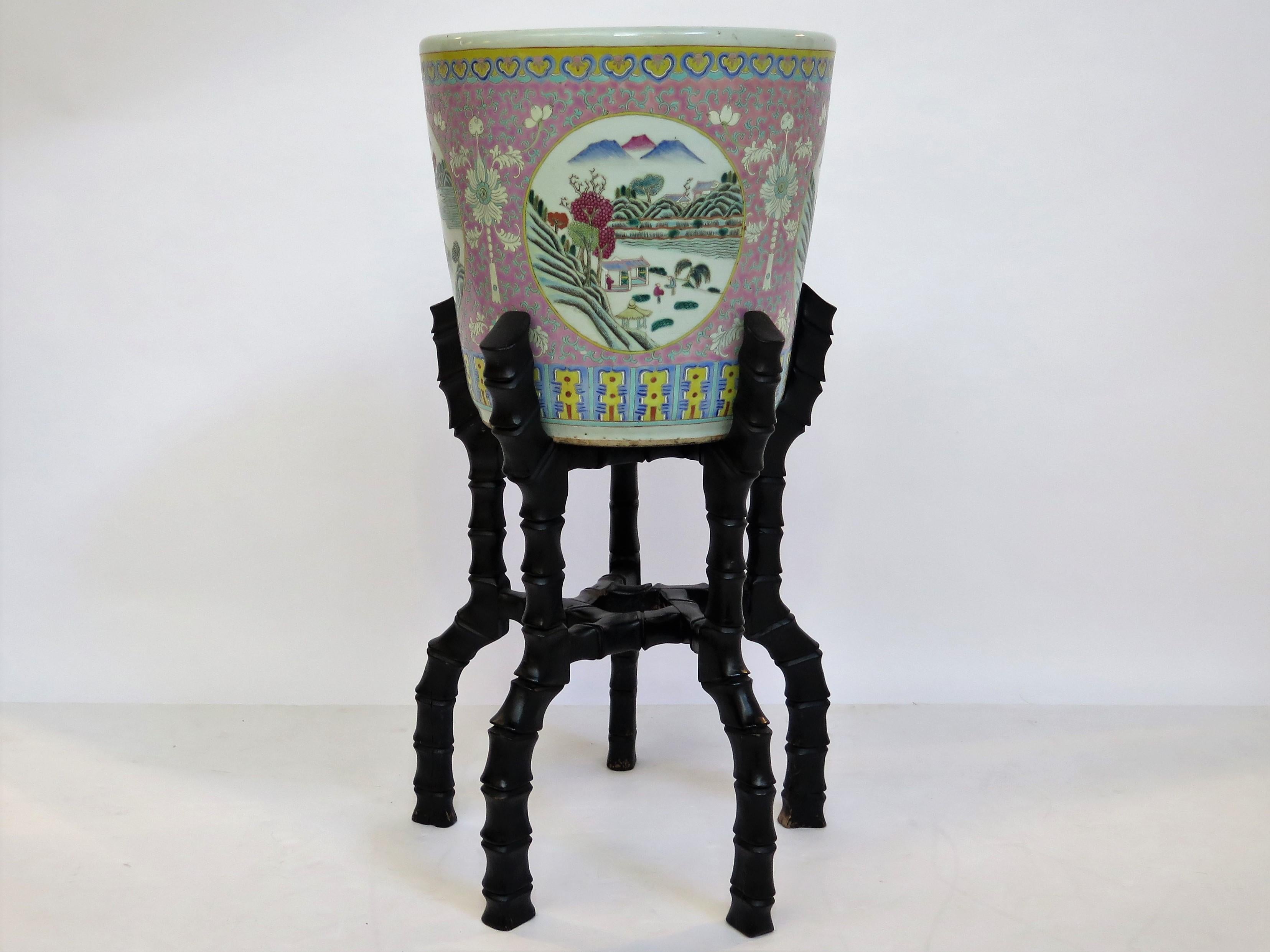 Beautiful large Chinese enameled porcelain jardiniere with carved wooden stand. Jardiniere features a white background with four round medallions depicting country life scenes. Decoration all around the lip of the jardiniere. Stamped CHINA on the