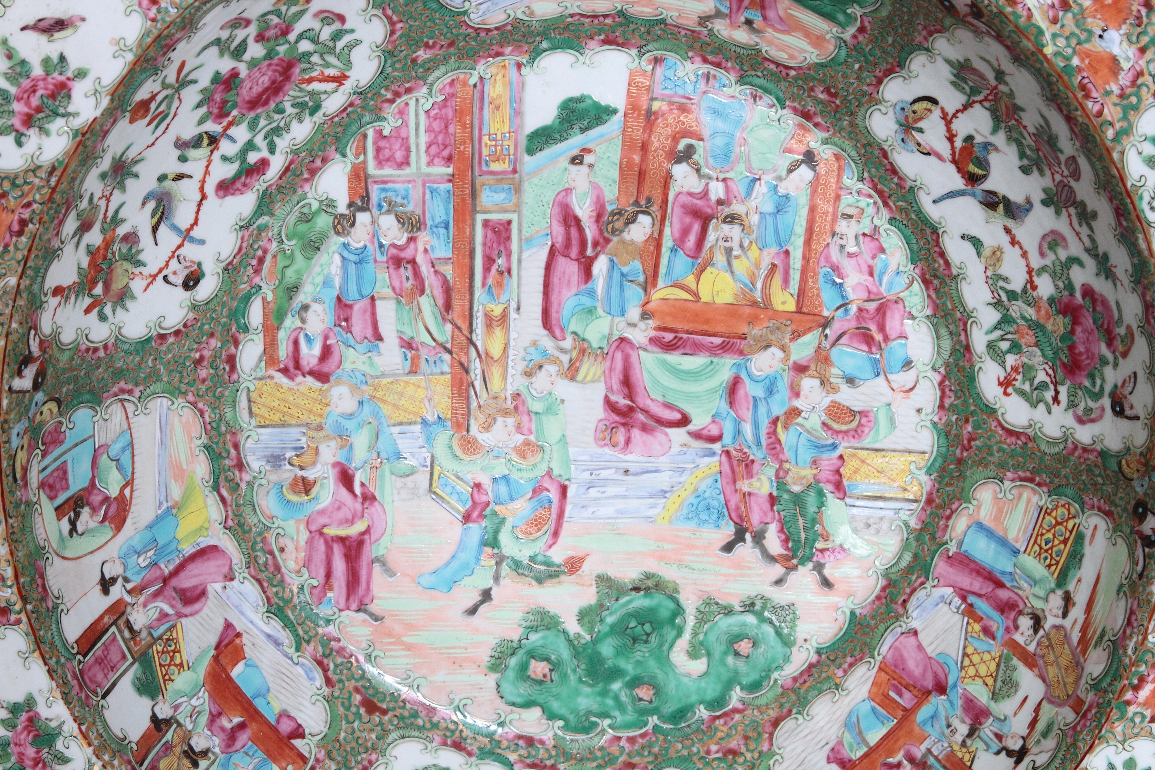 A large Chinese porcelain wash basin bowl in Rose Medallion pattern. Overall scenes with people, birds, butterflies and flowers in a famille rose palette with gold rim and orange peel texture.