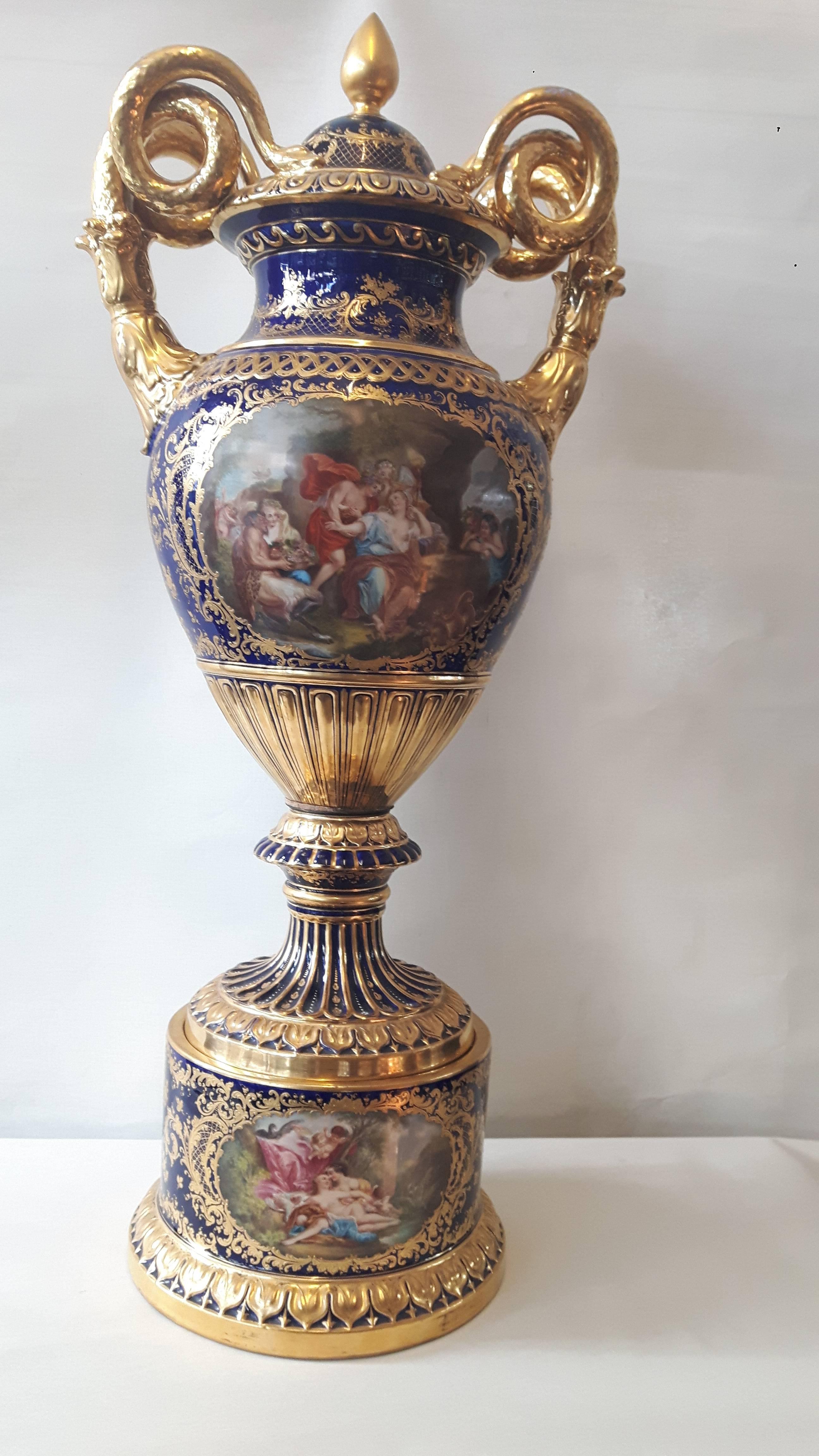 Un imponente vaso di Vienna in stile imperiale, dipinto a mano con cartigli di scene mitologiche greche. I manici in porcellana dorata hanno la forma di serpenti arrotolati e il corpo è ricoperto di motivi dorati.
Vienna, circa 1880.