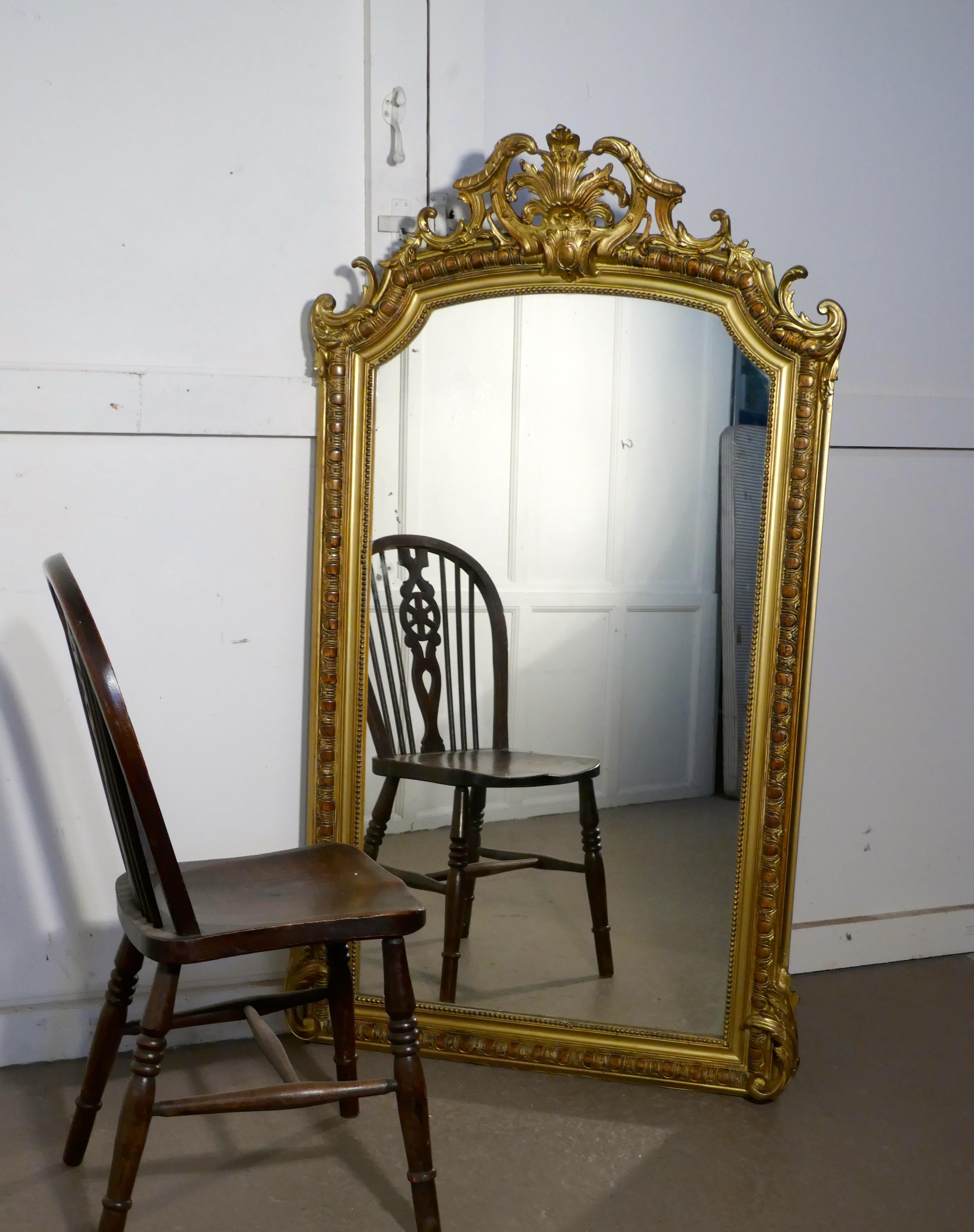 A large 19th century French gilt wall mirror

This mirror has a beautiful gilt and Gesso frame the carved frame is painted in a rich bright gold which has darkened slightly with age
The wide moulded frame is decorated and has an elegant