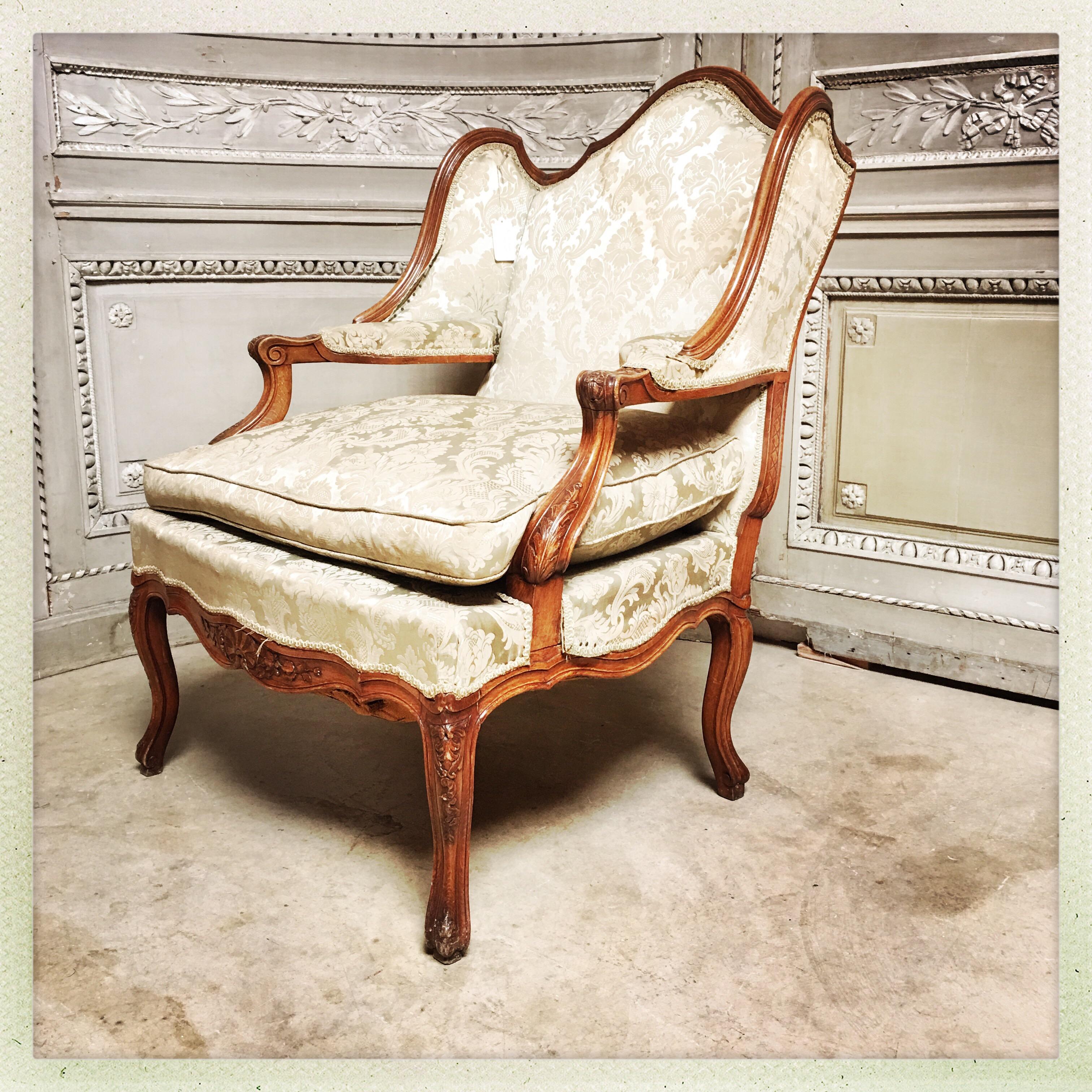 A large French carved walnut early Rococo style armchair with wings and interior armrest. 
Fauteuil en confessionnal in French.