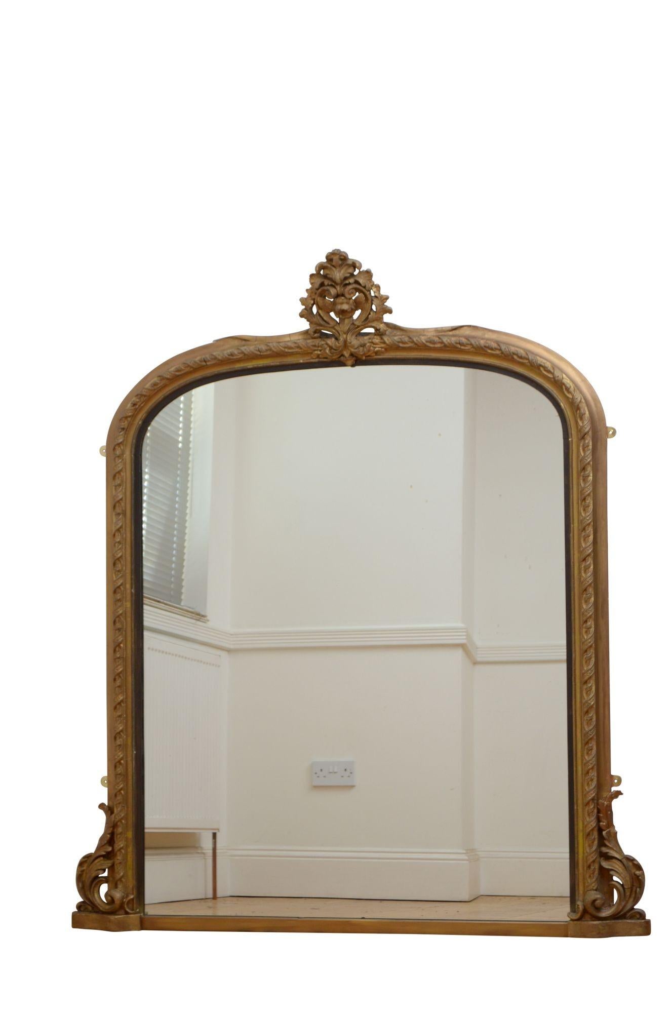 K0598 A large XIXth century giltwood wall mirror, having arched glass with minor imperfections in finely carved, moulded and gilded frame with leafy scrolls to the base and floral crest to the top. This antique mirror retains its gilt with touching