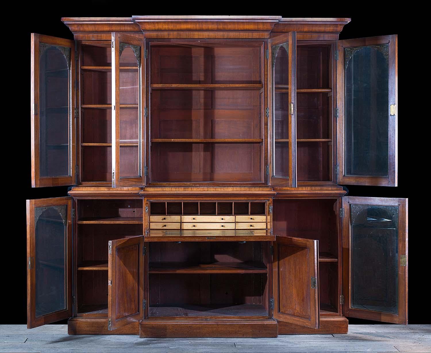 A very fine and large Victorian mahogany breakfront bookcase and secretaire. The upper part has four compartments, the doors of which are glazed with their original plate glass revealing the adjustable shelving within, the doors themselves have