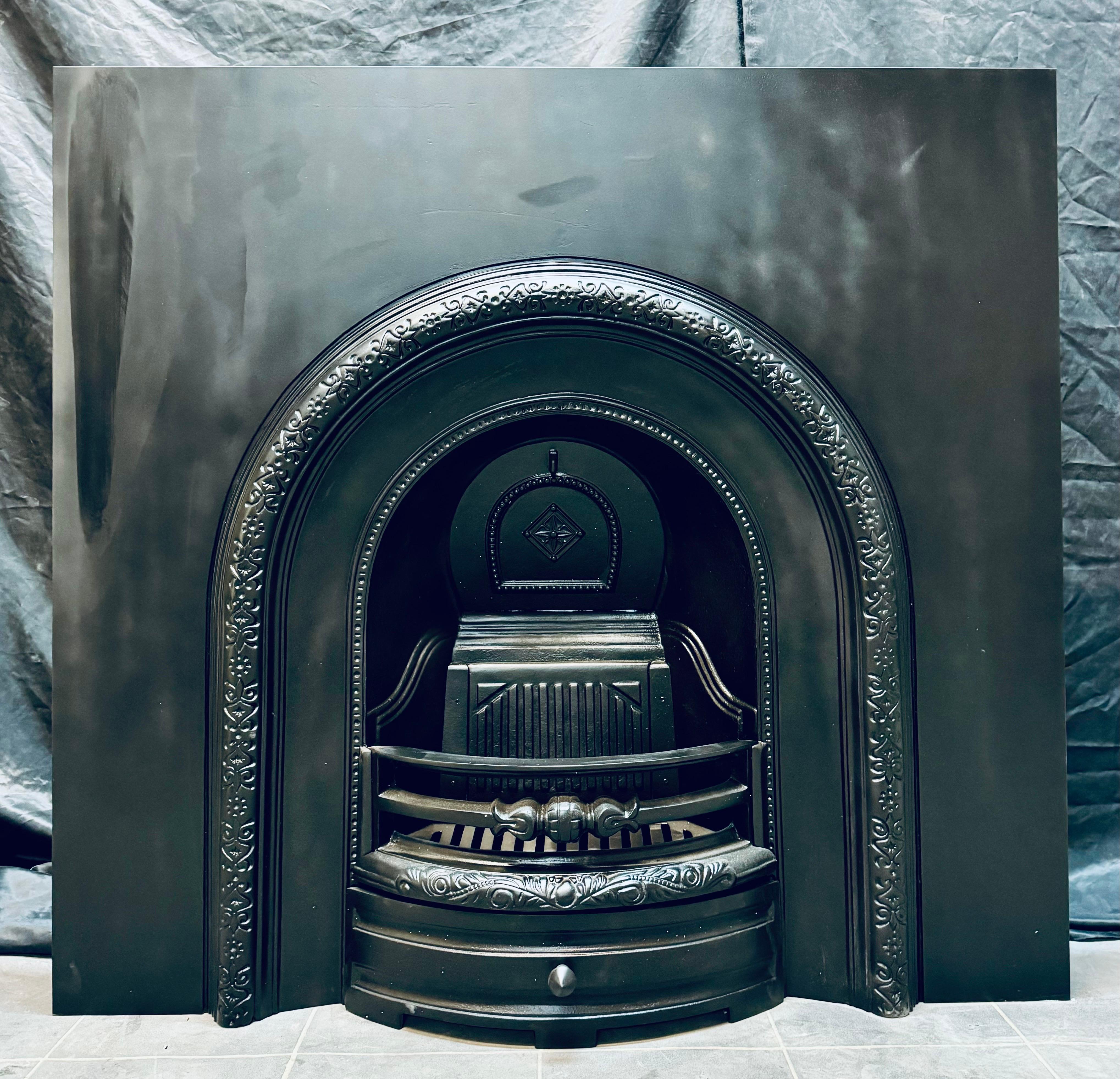 A large cast iron 19th Century Victorian manner fireplace insert. A substantial back plate that’s larger than normal, the arched raised border with the three barred curved fire front with ash pan door below. This piece is suitable for sold fuel or