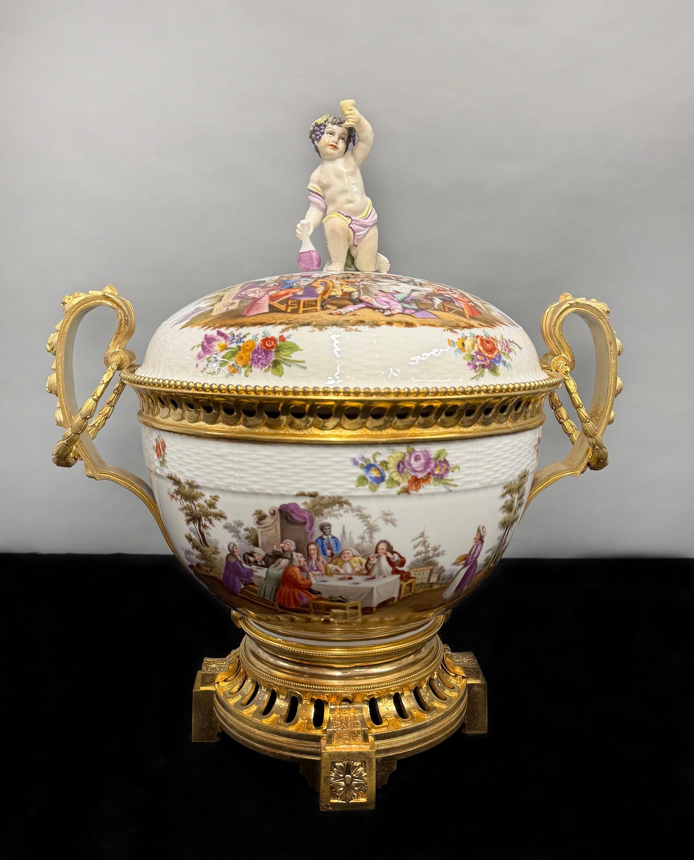 Un grande e fantastico centrotavola in porcellana di Berlino K.P.M. Berlin, montato in bronzo dorato, della fine del XIX secolo.

La ciotola con coperchio in porcellana finemente dipinta è sormontata da Bacco bambino e il suo vino, due grandi scene