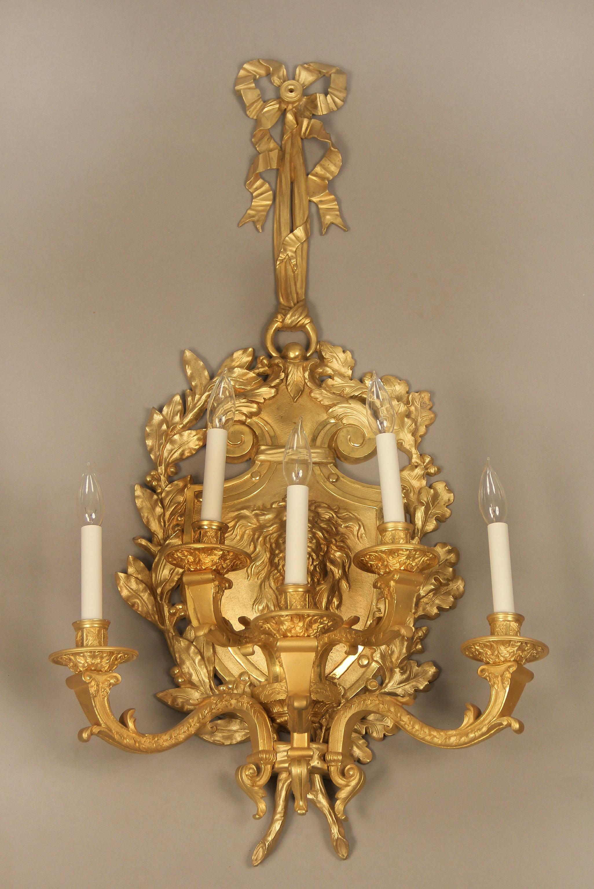 A large and fine pair of late 19th century gilt bronze 5-light sconces.

Centered with a mask of a bearded man with a lion pelt hat flanked by acanthus and laurel leaves along the sides, the top as a ribbon and bow, five tiered lights.