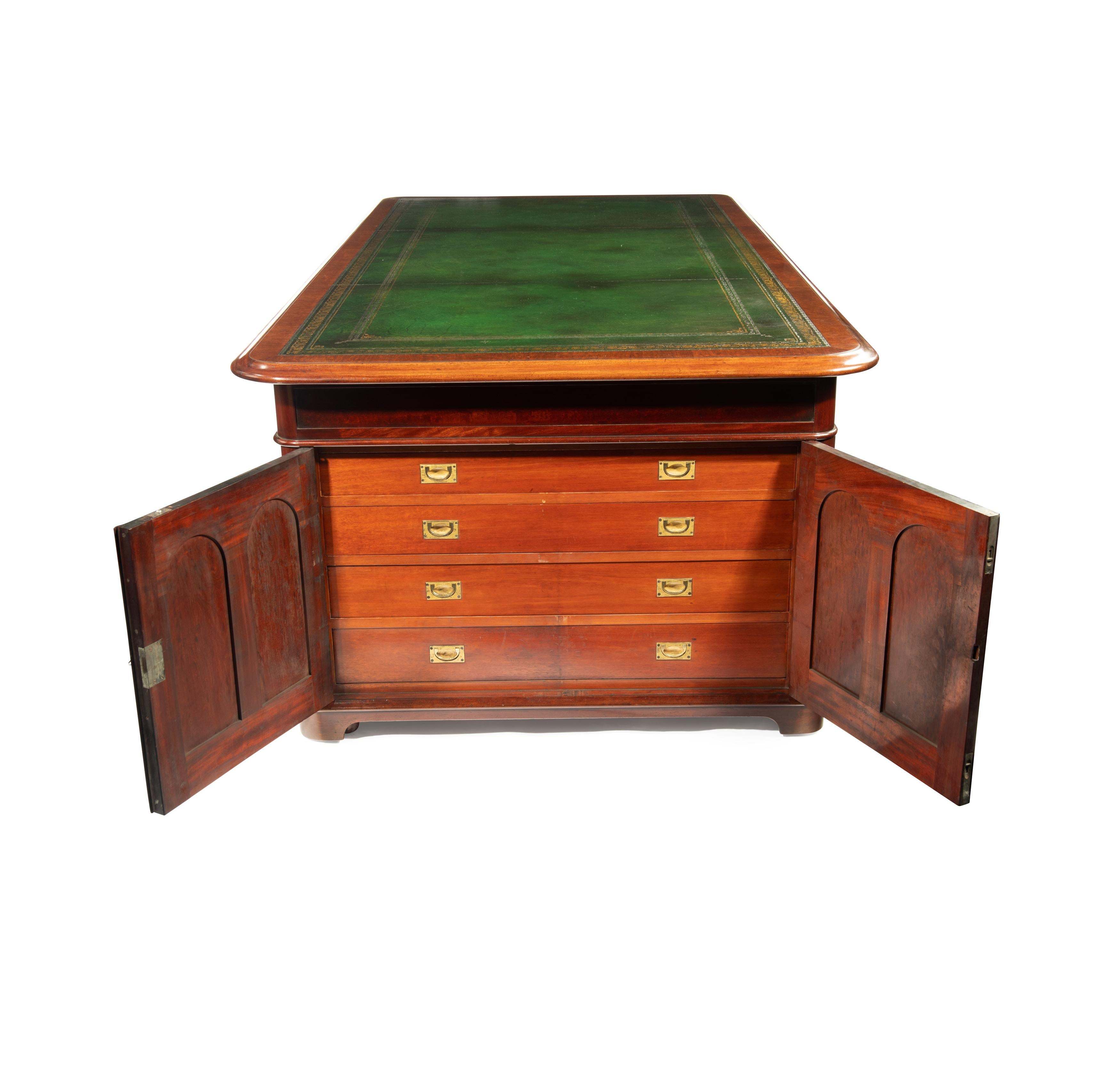 A large and imposing Victorian mahogany partners’ desk, the rectangular top inset with replaced green leather within cross-banding and a moulded edge, the frieze with three drawers which can be opened from either side and thus extend across the full