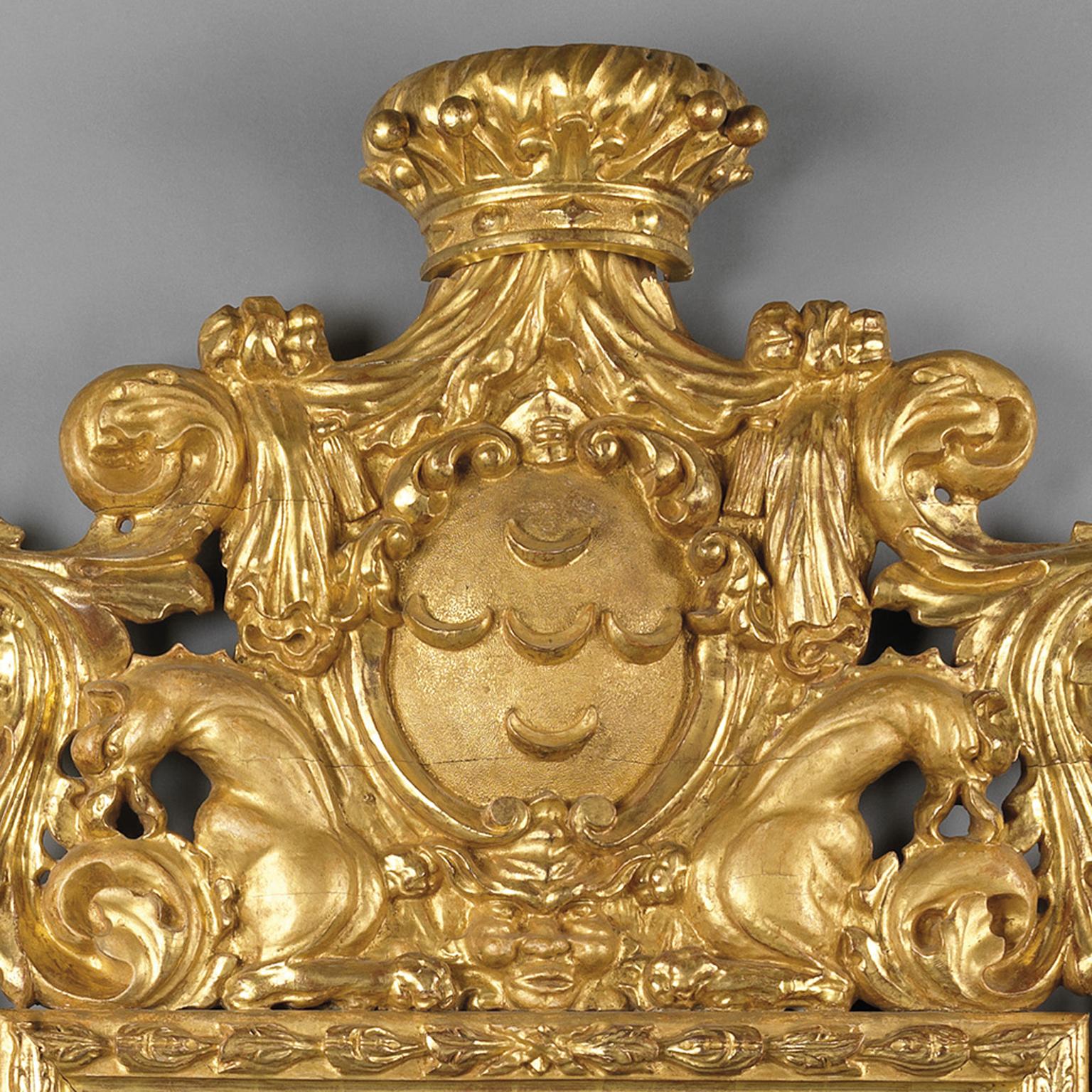 Un grand et impressionnant miroir en bois doré sculpté de style baroque, la plaque de miroir rectangulaire sous une crête composée d'une couronne et d'un cartouche à croissant de lune flanqué de bêtes stylisées et d'un cadre à guirlande de feuilles