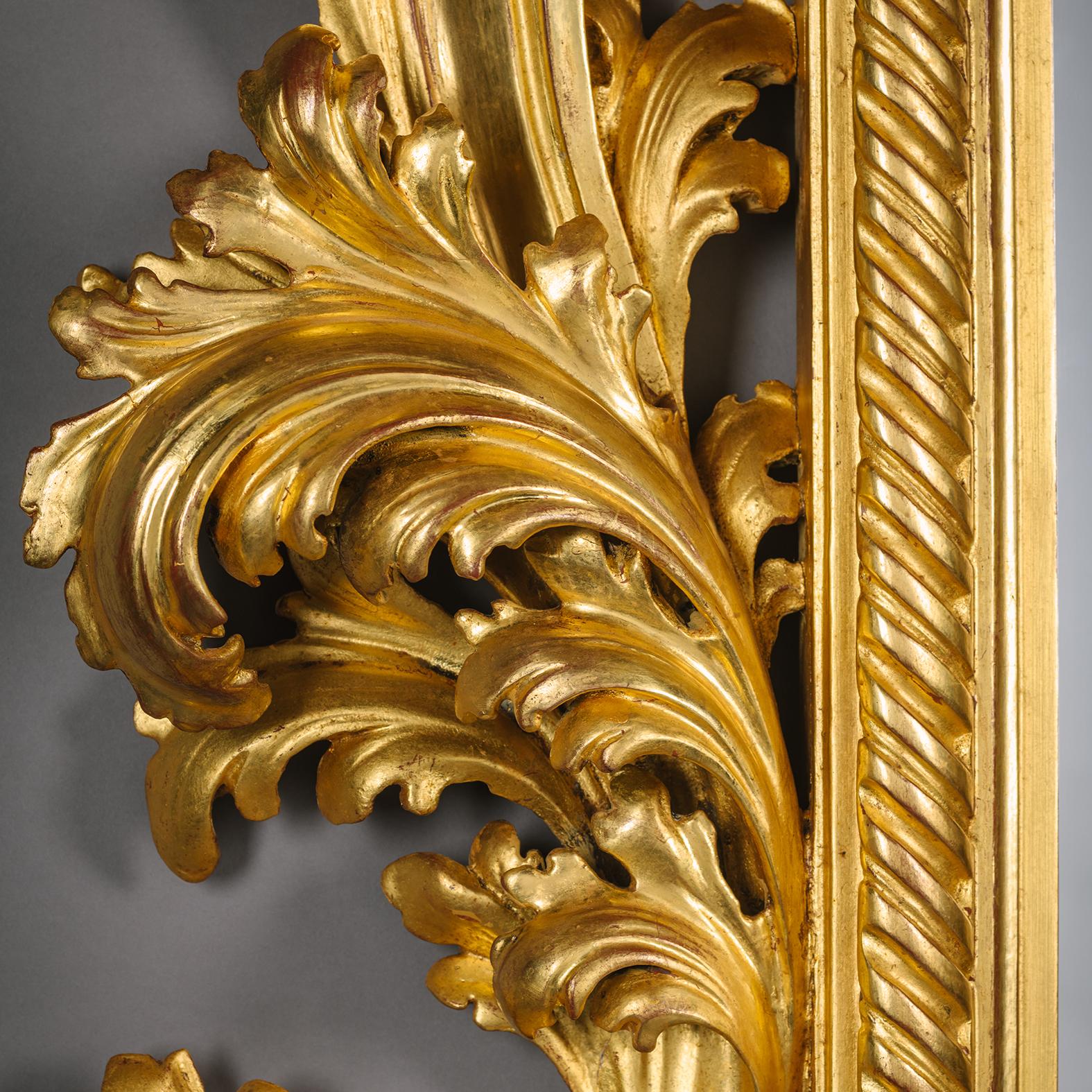 Un grande e imponente specchio in legno dorato intagliato in stile barocco.

La cornice rettangolare è elaborata con foglie d'acanto e volute. La cornice interna è incavata con nastri incanalati. La lastra di vetro smussata è un ricambio.

Le forme