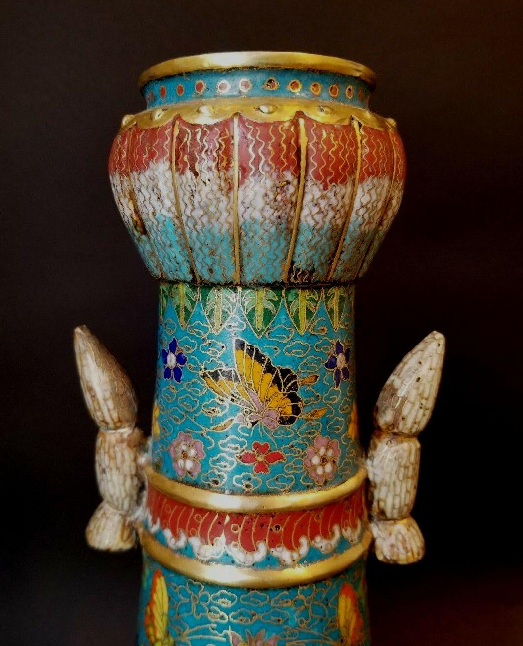 A large and impressive Chinese cloisonné enamel bottle-shaped vase. Featuring a floral and butterfly design and with lotus reliefs and handles. Incised mark at base. A Heavy piece and signed on the bottom.