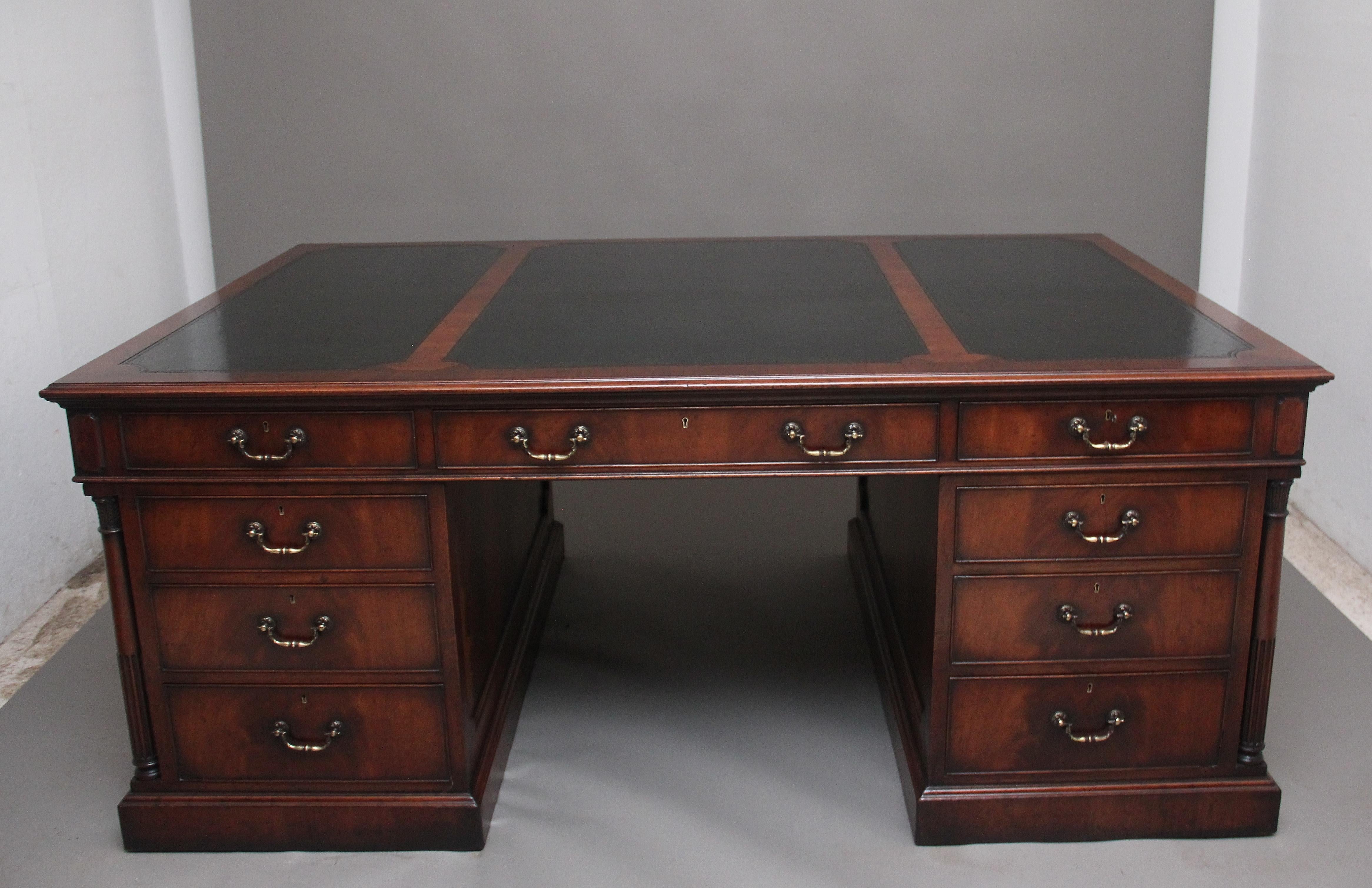 A large and impressive early 20th century mahogany desk, the moulded edge top having a green leather writing surface divided into three shaped sections, the front of the desk having an arrangement of nine long graduated mahogany lined drawers with