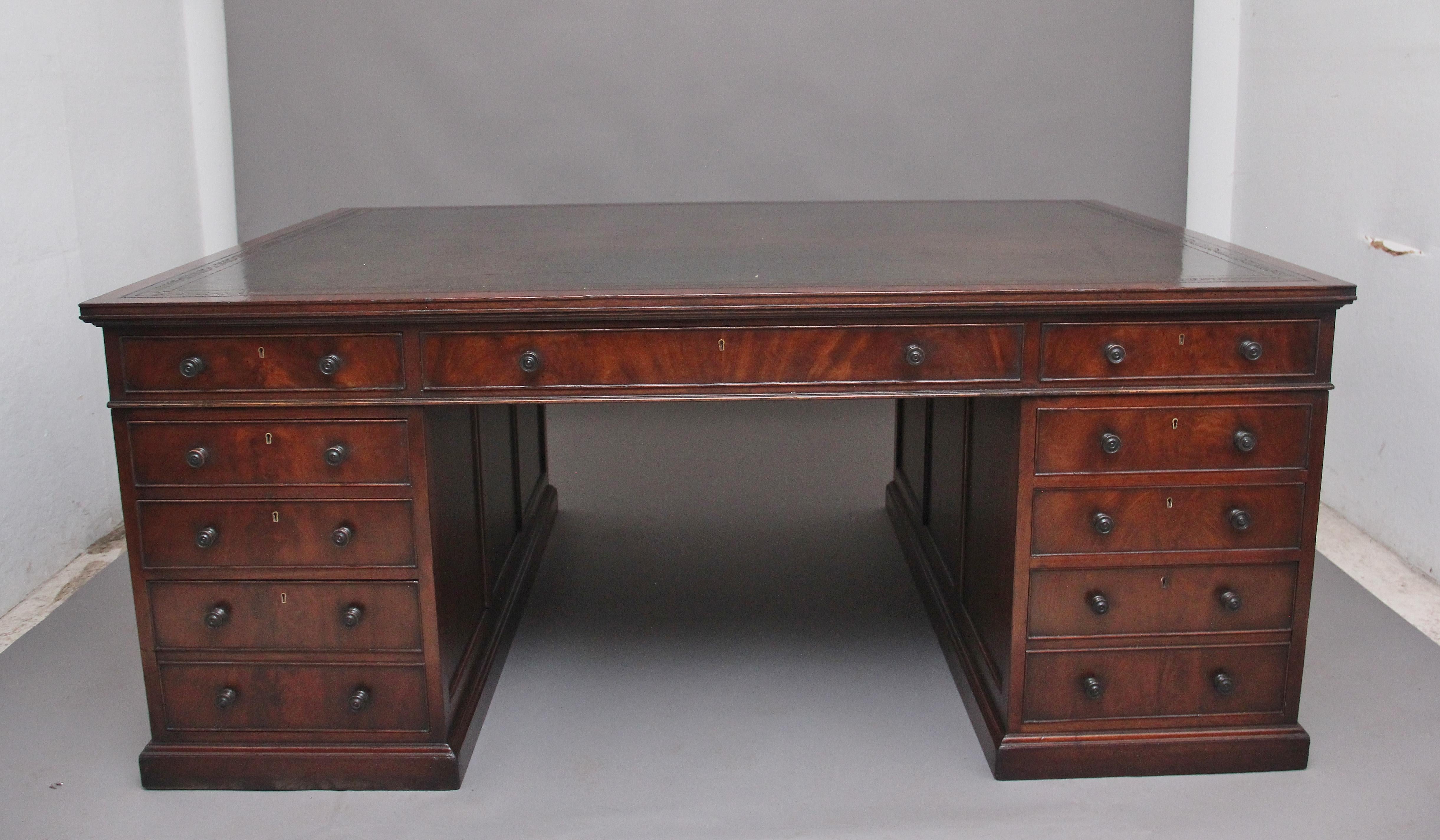A large and impressive early 20th Century mahogany partners desk, having the original green leather writing surface decorated with gold and blind tooling, having an arrangement of nine mahogany lined graduated drawers on one side with a double
