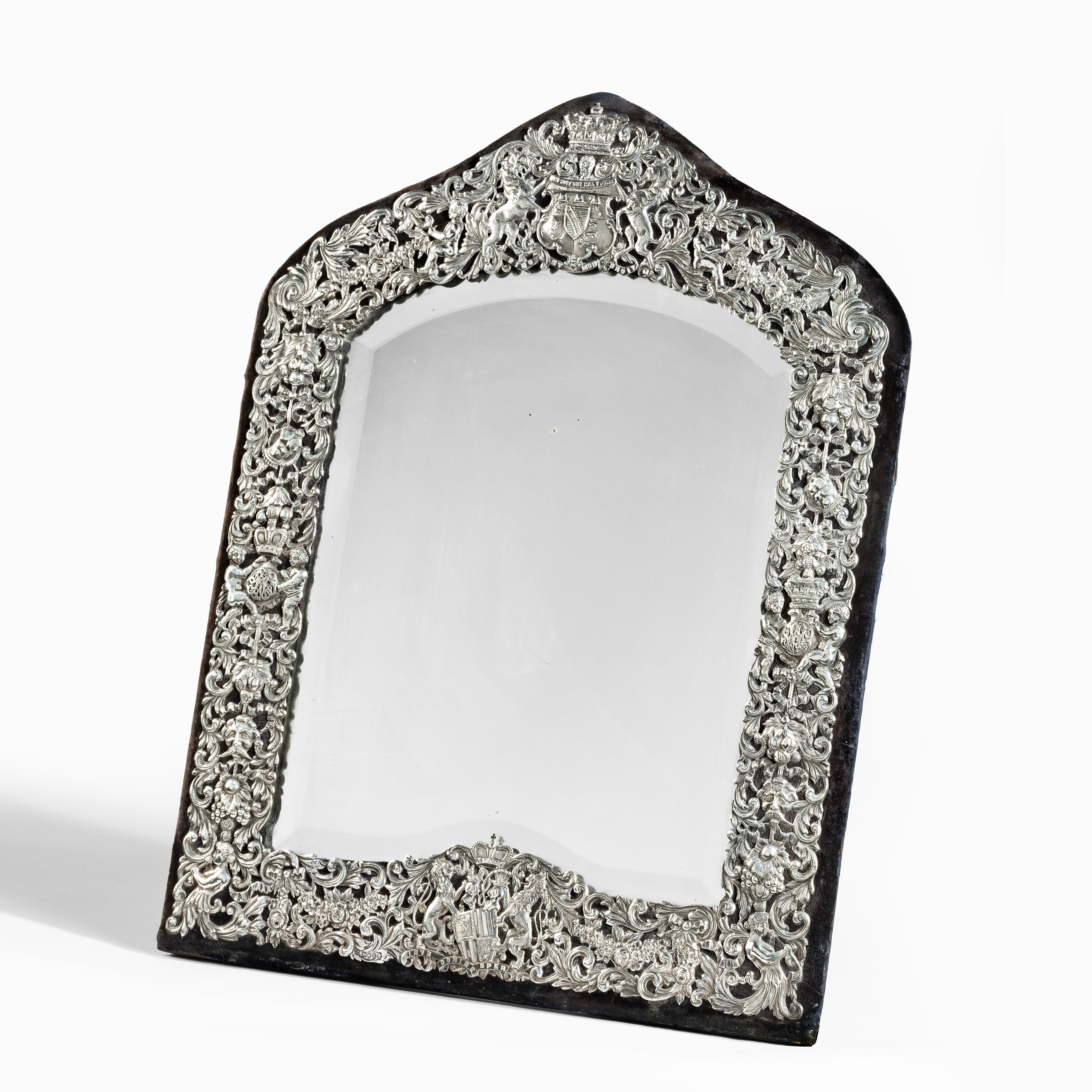 Ce grand miroir de table argenté et orné présente un arc pointu au-dessus de la plaque d'origine. Le cadre ajouré en argent ciselé et repoussé est appliqué sur un fond de velours bleu royal mat et comprend une abondance de motifs classiques couchés