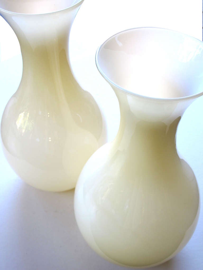 A large and shapely pair of Murano 1970s butter-cream cased glass vases; each tall vase with long flaring neck above a bulbous body; the white vase encased in a yellow cased glass.