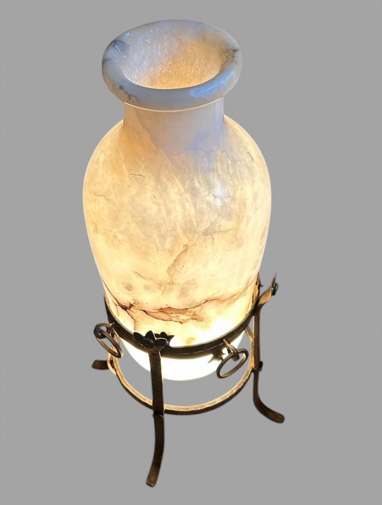 Une grande et inhabituelle urne en albâtre très attrayante sur un support en fer forgé vers les années 1930. Le haut du vase se détache pour permettre l'éclairage et le col du vase est suffisamment profond pour être utilisé comme récipient pour les