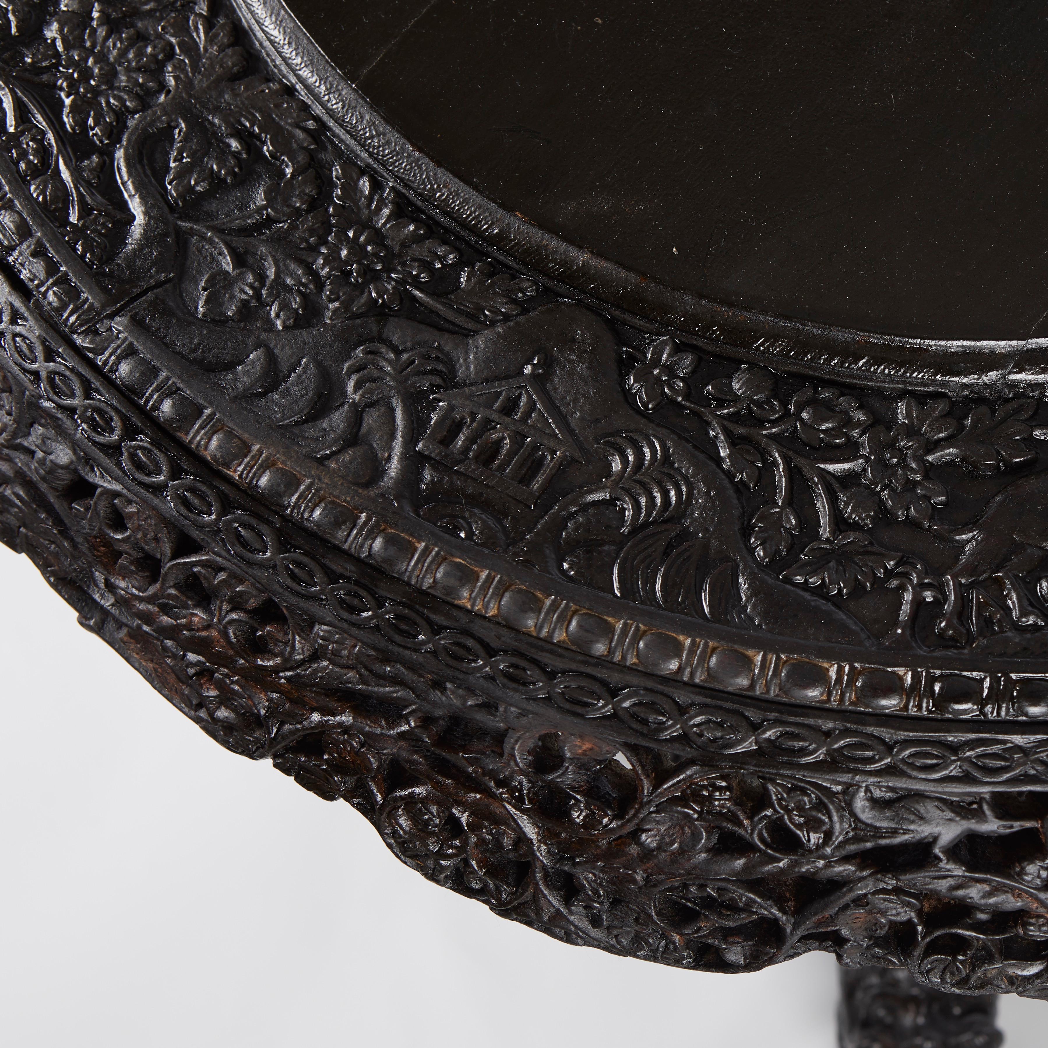 An Anglo-Indian side table with heavily carved shaped apron having pierced decorations. The pedestal base with vase and leaf shaped carved decoration supported. by base with pierced carving and stylized dragon form legs. Circa 1900.