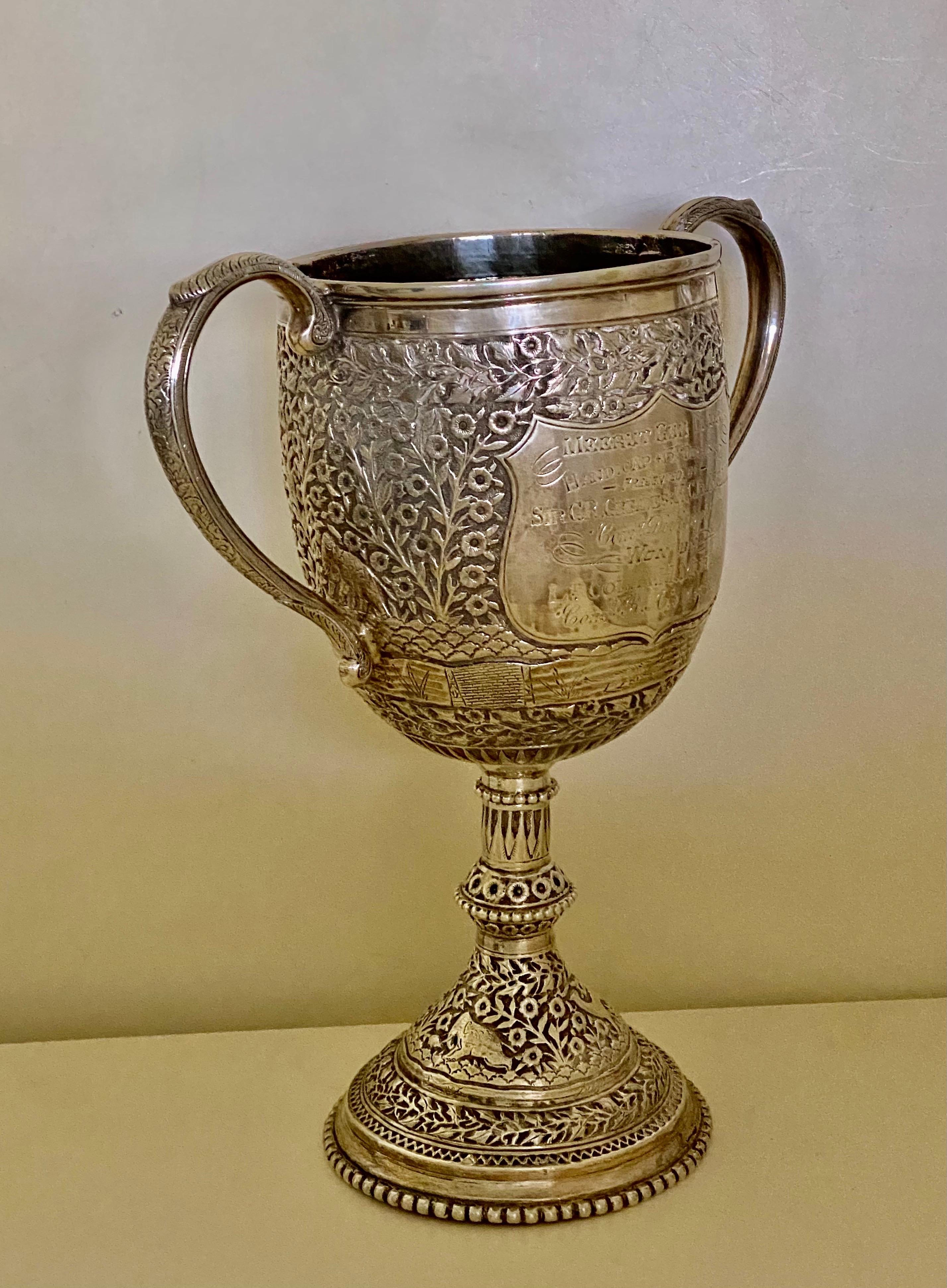 A large antique 19th century Indian Silver Kutch trophy cup with twin cast handles, the body is profusely chased with the typical repousse' foliage, also depicting flowers and animals, very crisp and detailed A shield on the front side. The silver