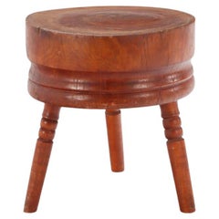 A large antique butcher block table having a natural circular top.