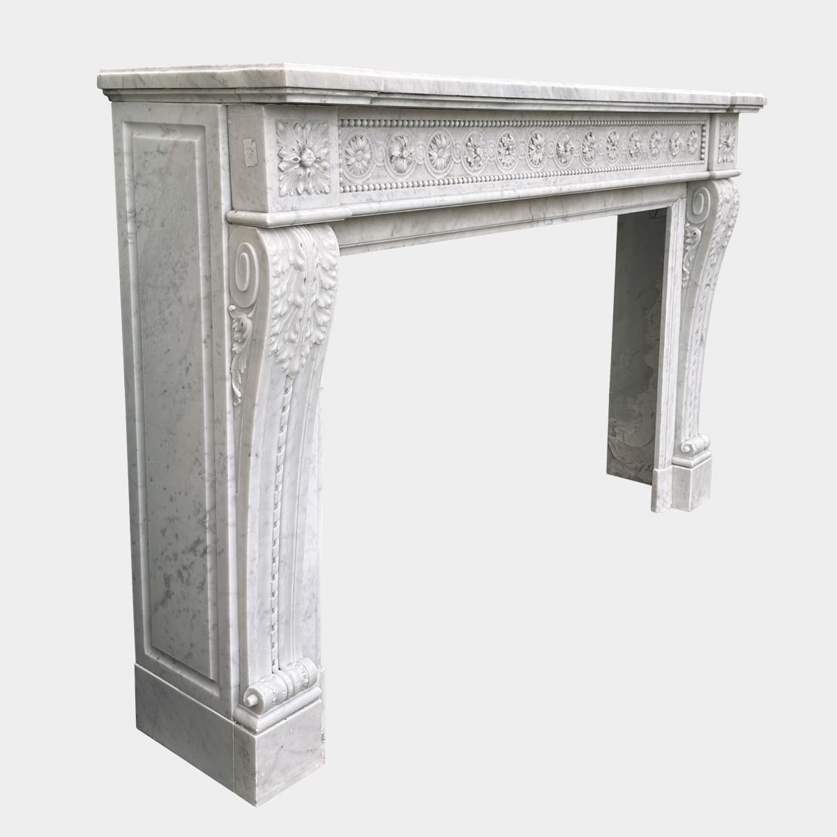 Grande et impressionnante cheminée de style Louis XVI en marbre de Carrare italien. Les pieds en console à enroulement sont décorés d'un ruban torsadé, d'une acanthe sculptée dans la partie supérieure et d'une volute sculptée dans la partie