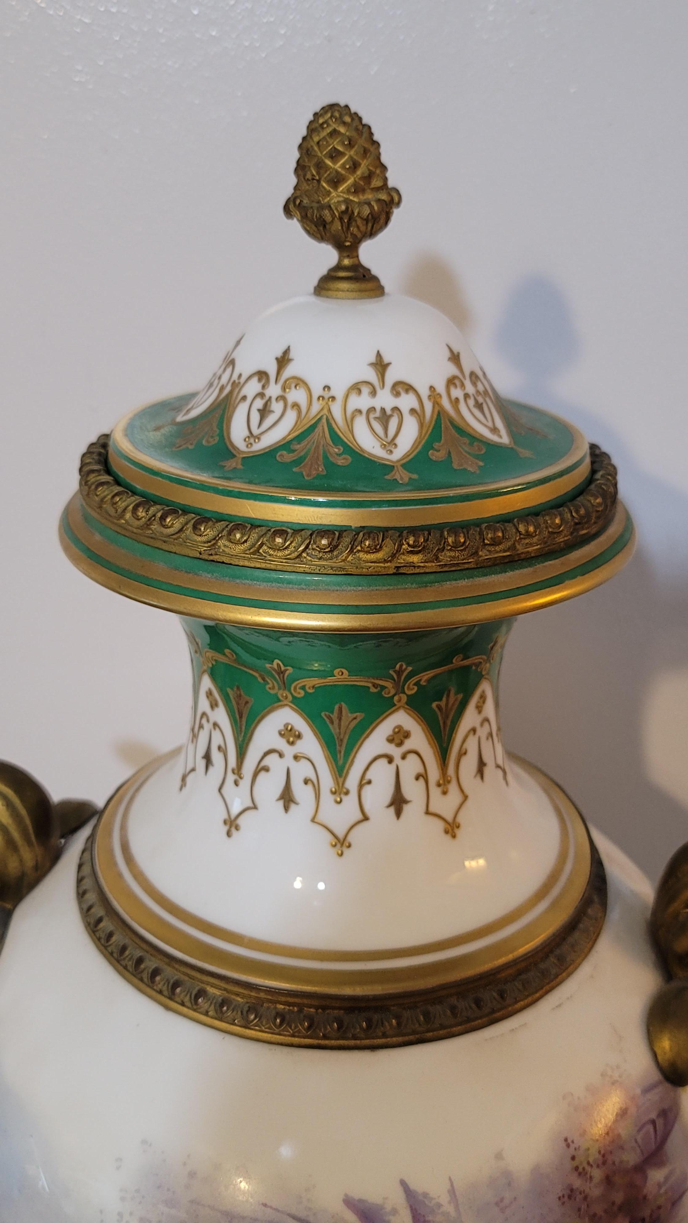 A large 19th century antique Sevres Porcelain Urn featuring in white and green ground color, decorated with scenes of courting couples and floral bouquet motifs, further fitted with ornate gilt bronze applications. Artist Signature on the Painting