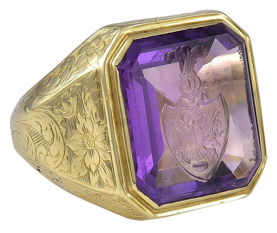 This wonderful looking Ring is set with a fine Amethyst engraved with an Armorial Crest, the shield with an armoured breast plate and helmet with a surround of trophies. Above the shield is a Knights Helmet mounted with 3 ostrich plumes.
These large