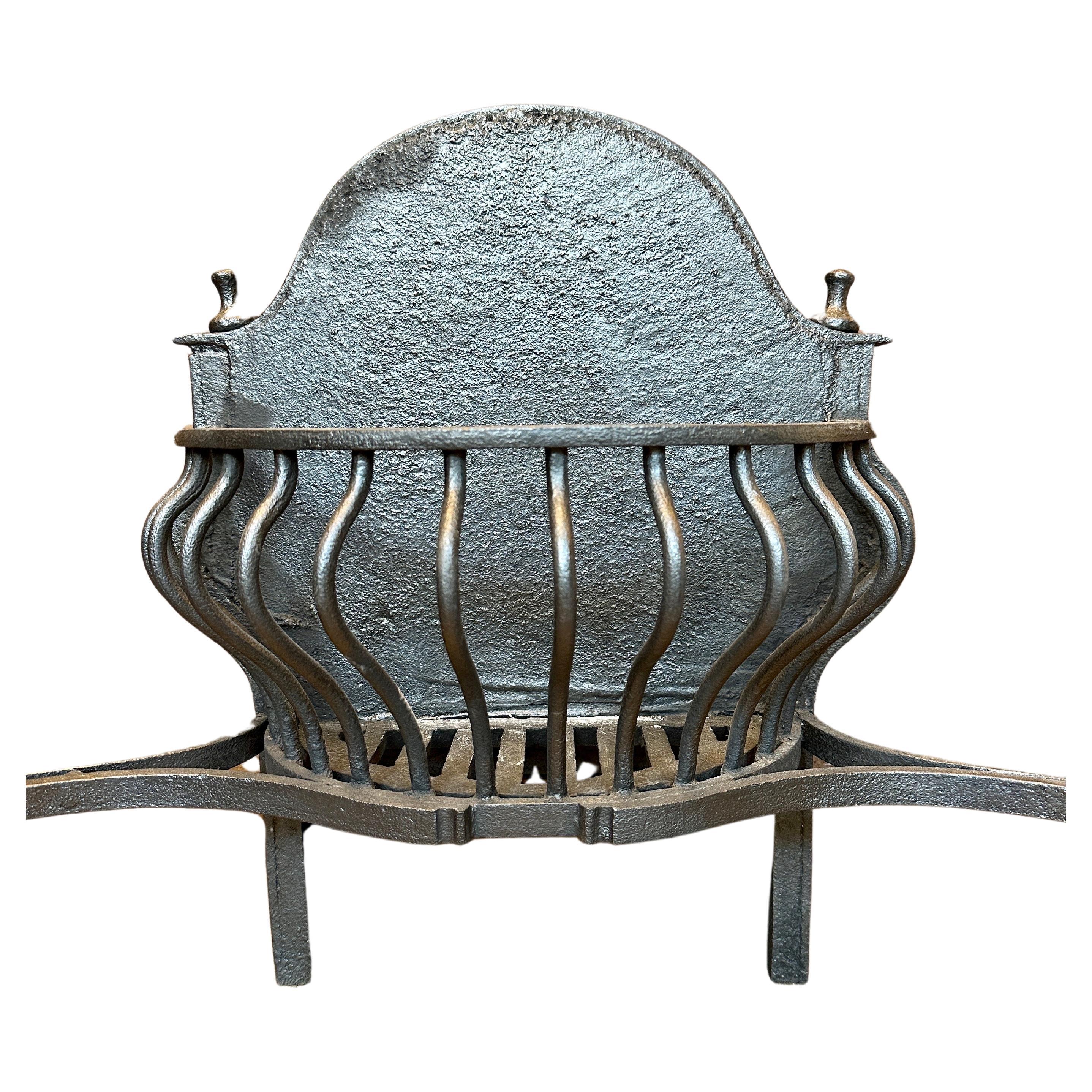 A large and impressive Gothic Revival fire grate in wrought iron with brick fire back. The front supports swept out on splayed feet with curved elongated uprights with dragons heads with ringed mouths. The burning area of curved balustrade bars and