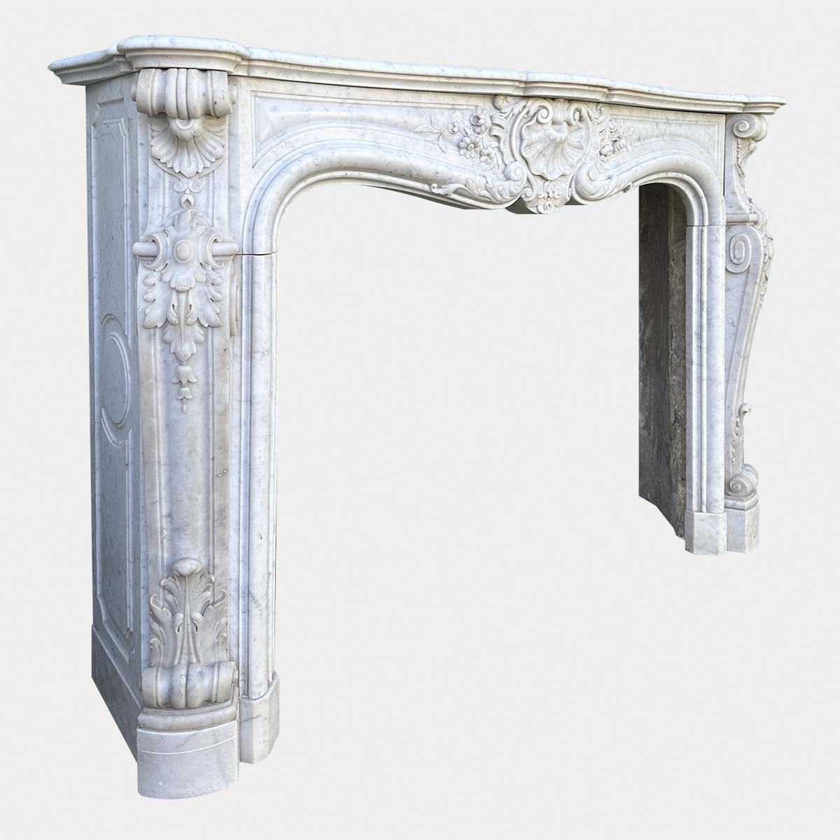 A very good quality late 18th c Louis XV marble fireplace. Executed in Italian Carrara marble, with superior carvings in the Rococo taste. The serpentine shelf above a paneled frieze with an  A symmetrical carved central cartouche typical of the