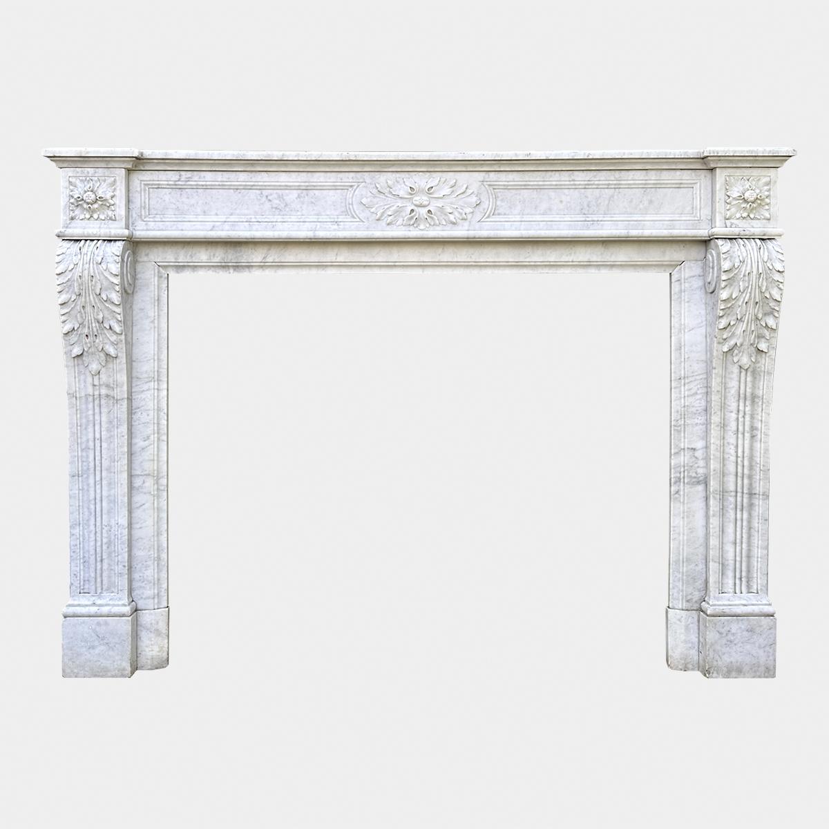 A large Louis XVI style Carrara Marble fireplace dated from the mid 19th century. The console jambs with carved acanthus and tapering panels, with square Patarae corner blocks. The frieze with centre Patarae flanked by fielded panels. The side