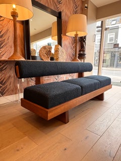 A large architectural bench with a back rest in navy blue boucle .made to order