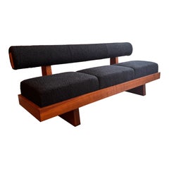 A large architectural bench with a back rest in navy blue boucle .