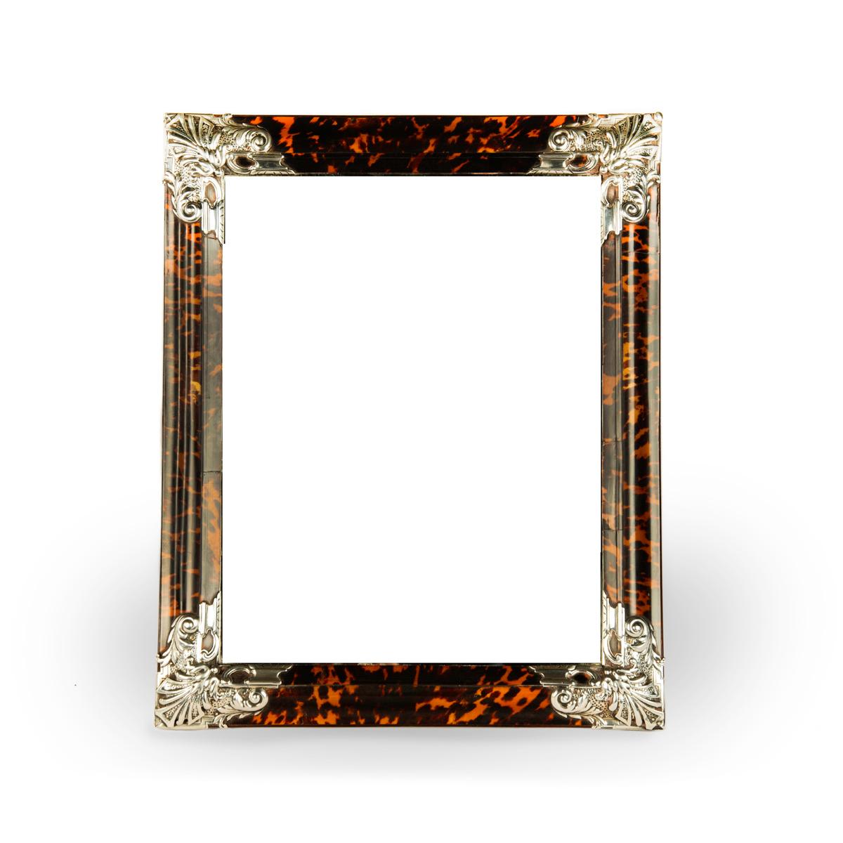 A large Art Deco silver mounted tortoiseshell easel mirror, the rectangular plate framed in tortoiseshell with large silver mounts applied to the corners comprising athemions with squared off petals and scrolls, the reverse with a stand and a