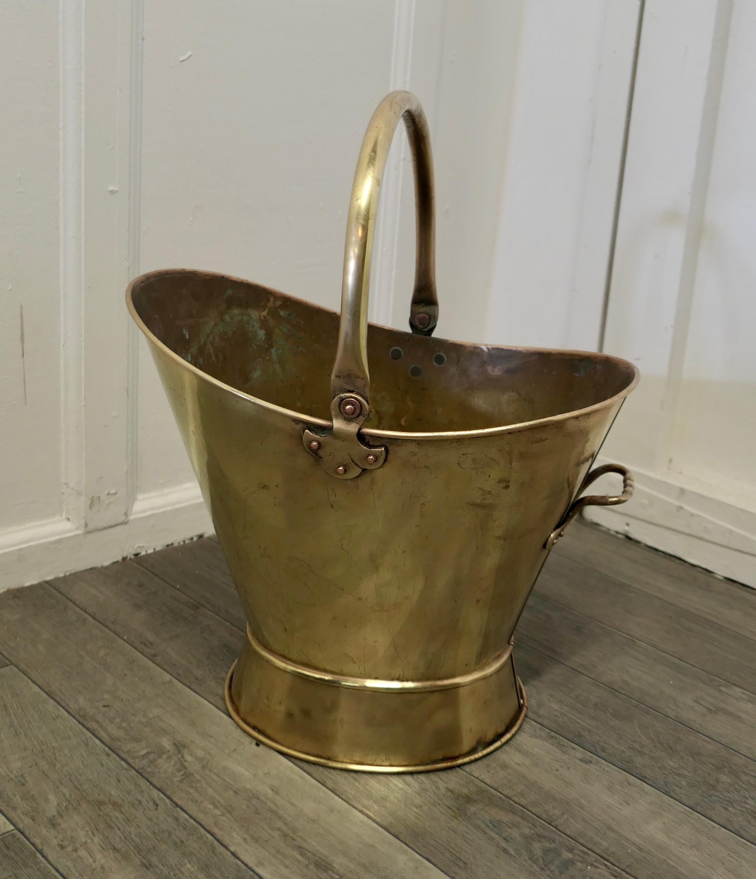 A large Art Nouveau brass helmet coal scuttle.

This is a very attractive bucket is has an open oval shape with an upward sweeping side and an extra handle at the other, it has a swing handle on top 
The scuttle is in very good used condition,