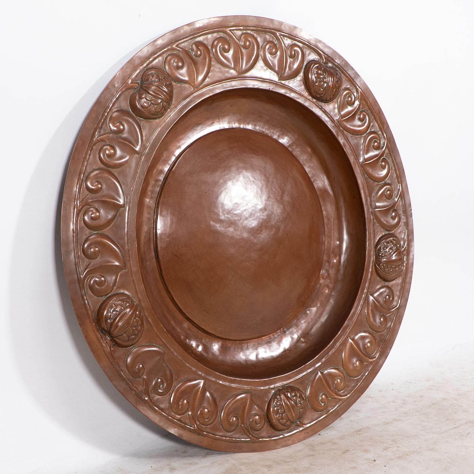 English A large Arts and Crafts hand formed copper charger with stylized decoration For Sale