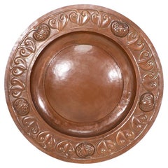 A large Arts and Crafts hand formed copper charger with stylized decoration
