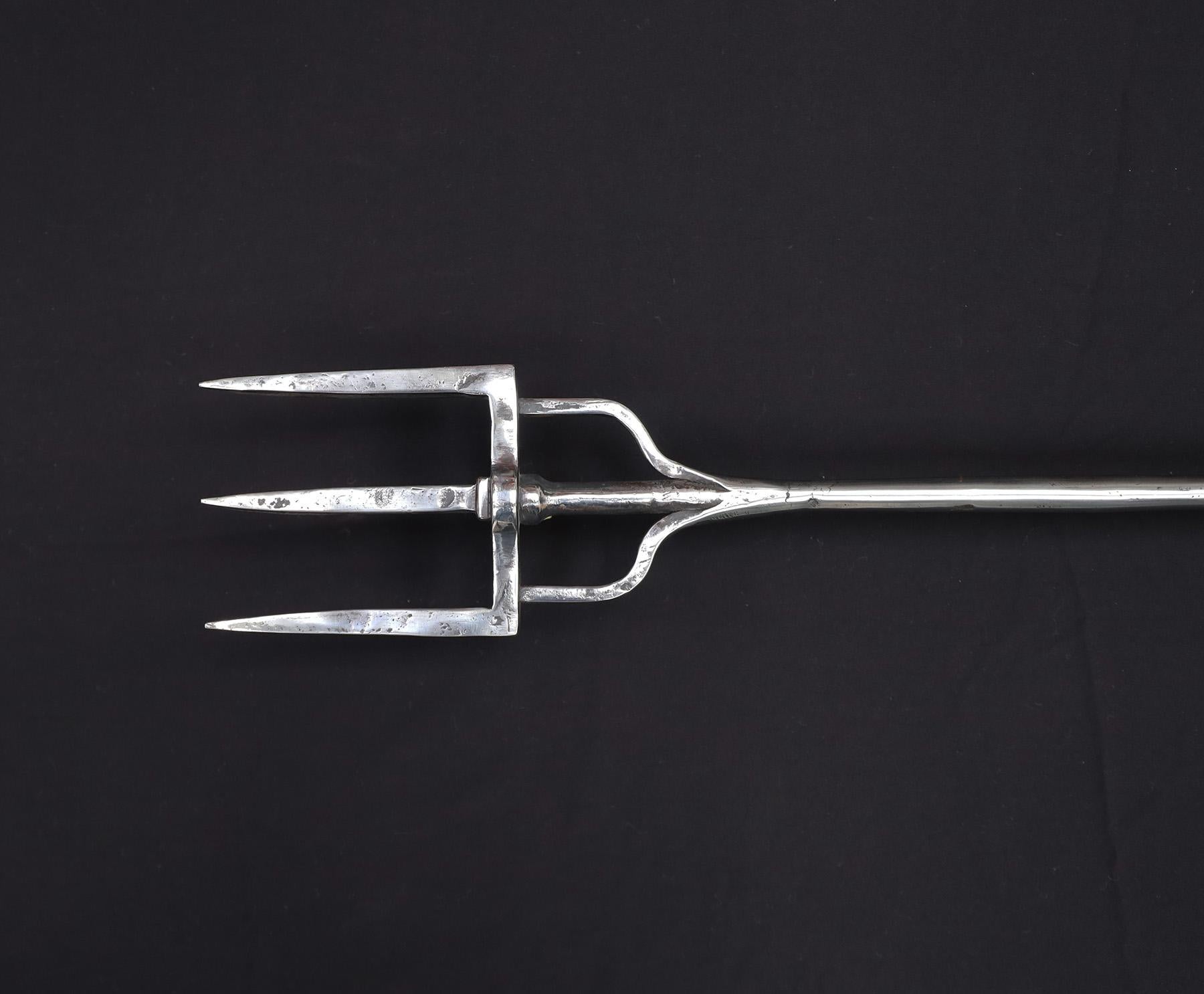 A large Arts and Crafts wrought-iron fireplace log fork. A three pronged fork with rear log hook, open-nest detail to shaft and top with bulbous finial to handle. Restored.
Circa 1900