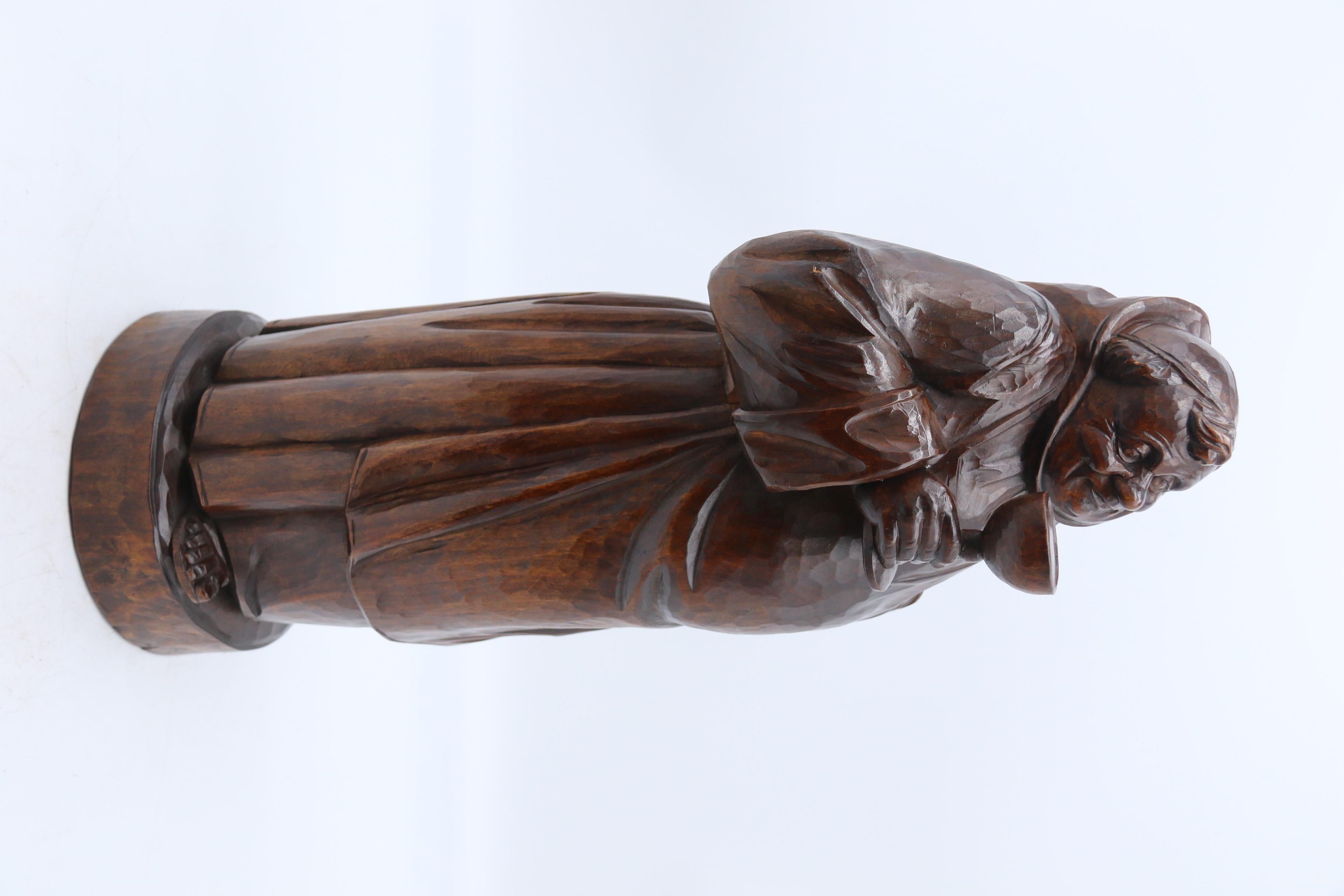 Cette impressionnante figurine de grande taille en bois de tilleul de la Forêt-Noire est magnifiquement sculptée et représente un moine corpulent, vêtu d'un simple habit, qui déguste gaiement un grand gobelet de vin ou peut-être plusieurs à en juger