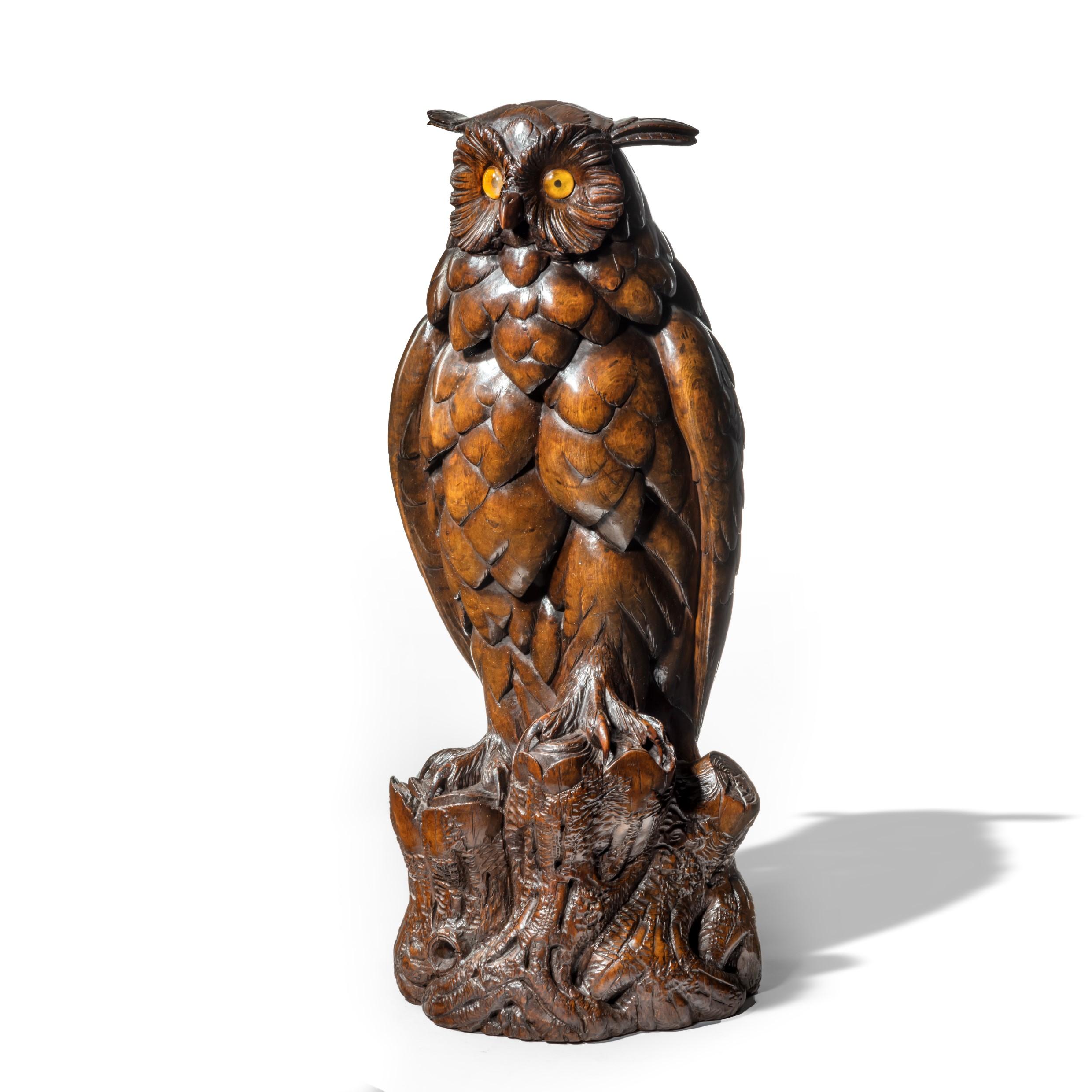 A large Black Forest Lindenwood eagle owl attributed to the Ruef Brothers, standing four square on a gnarled branch with yellow foil-backed glass eyes and naturalistic feathers. Swiss circa 1880.

Footnote: For a very similar tobacco jar also