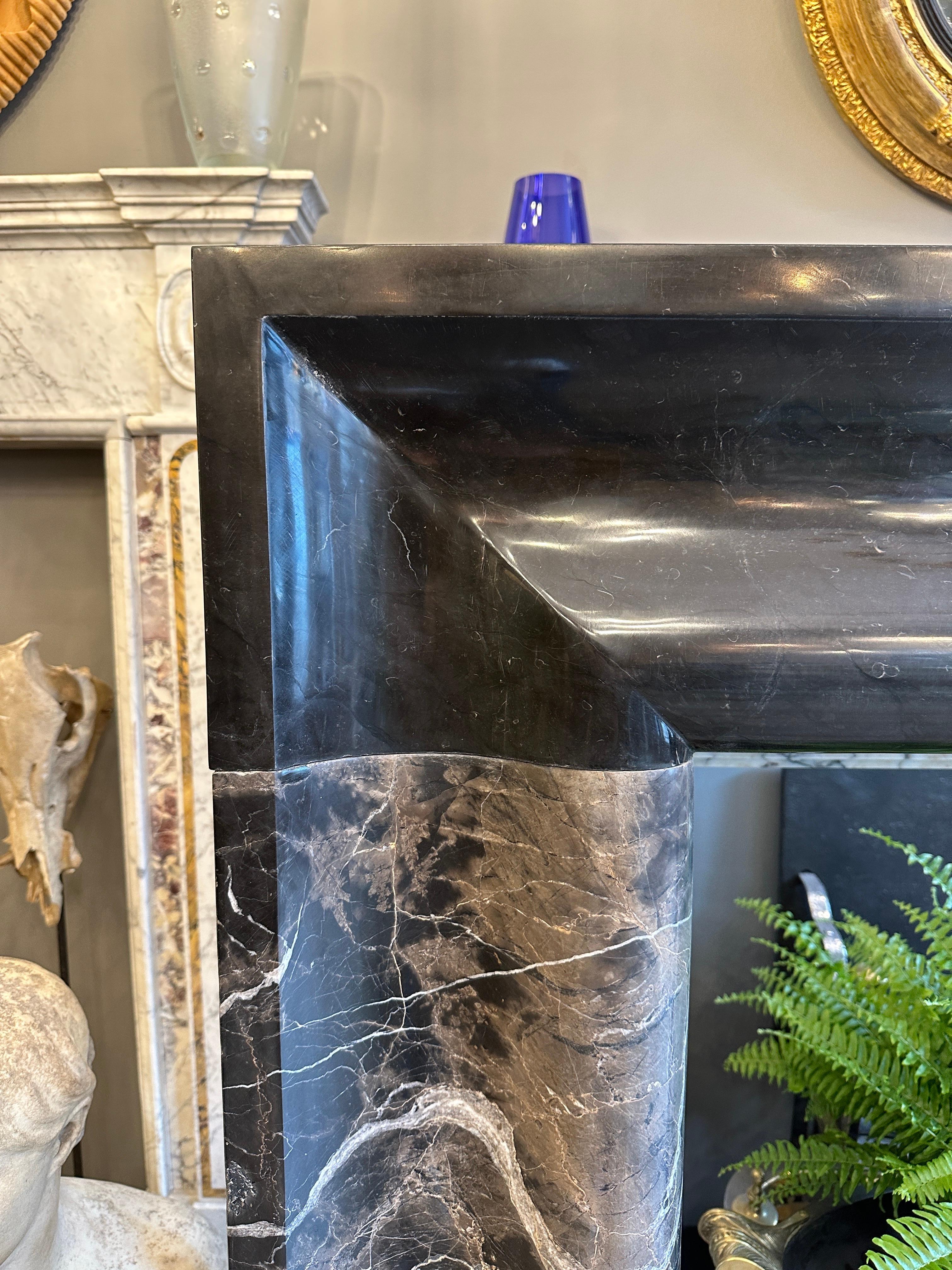 A large and substantial Bolection fireplace surround in a richly variegated black Nero Marquina marble. The wide moulding to jambs and header although traditional give a contemporary aesthetic. All supported on large square block feet. Mantle length