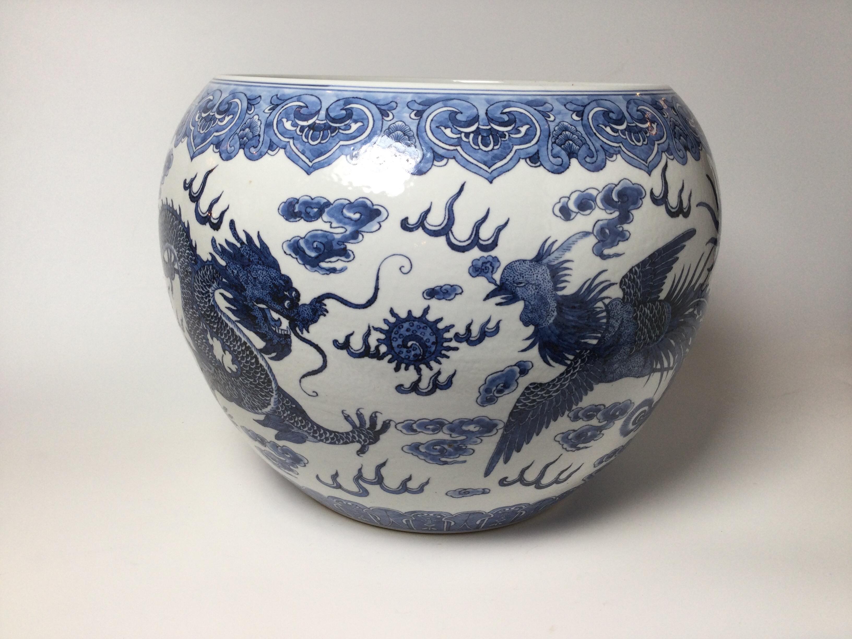 Classic Chinese blue and white porcelain jardinière with hand painted cobalt decoration. The white porcelain with painted Dragon and Phoenix bird decoration. Measures: 14.5 inches diameter, 12 inches tall.
