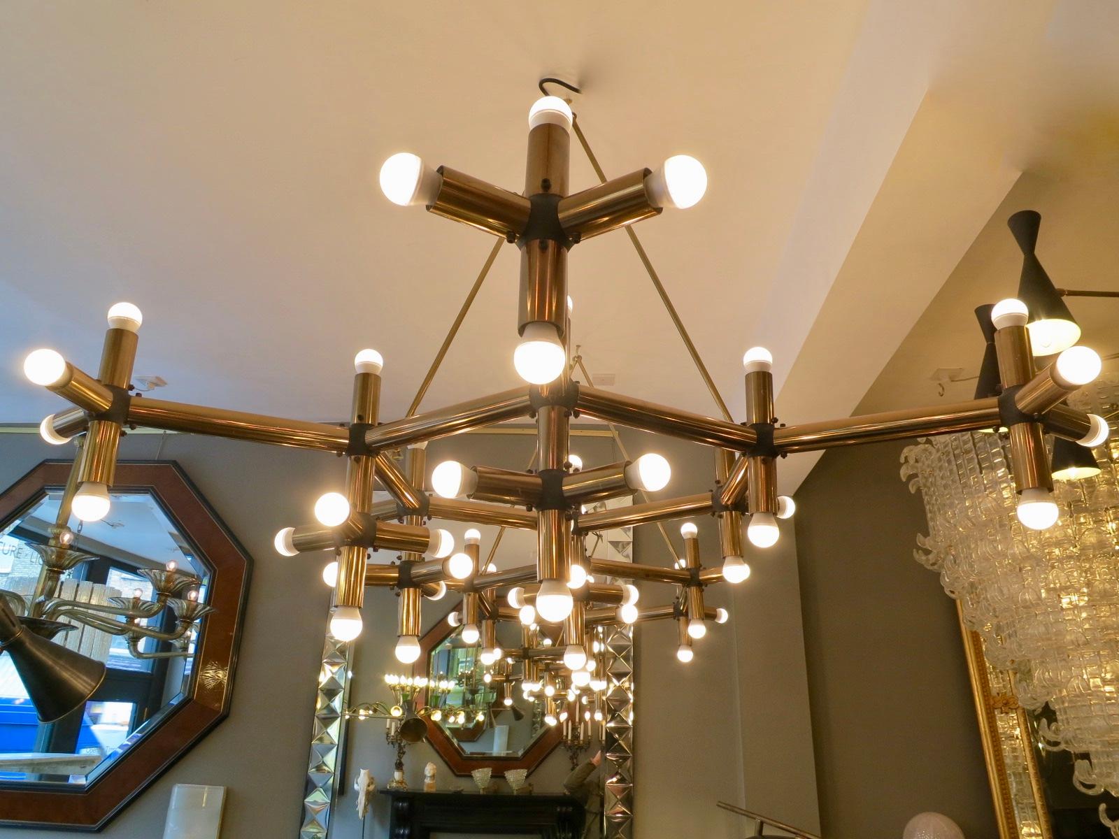 An unusual and very large tubular geometrical “ lichtstruktur “ chandelier in brass by Robert Haussmann. Having 54-light fittings. Hung from the ceiling with brass matching hooked rods. Imported from Paris and installed in Mayfair London. Then