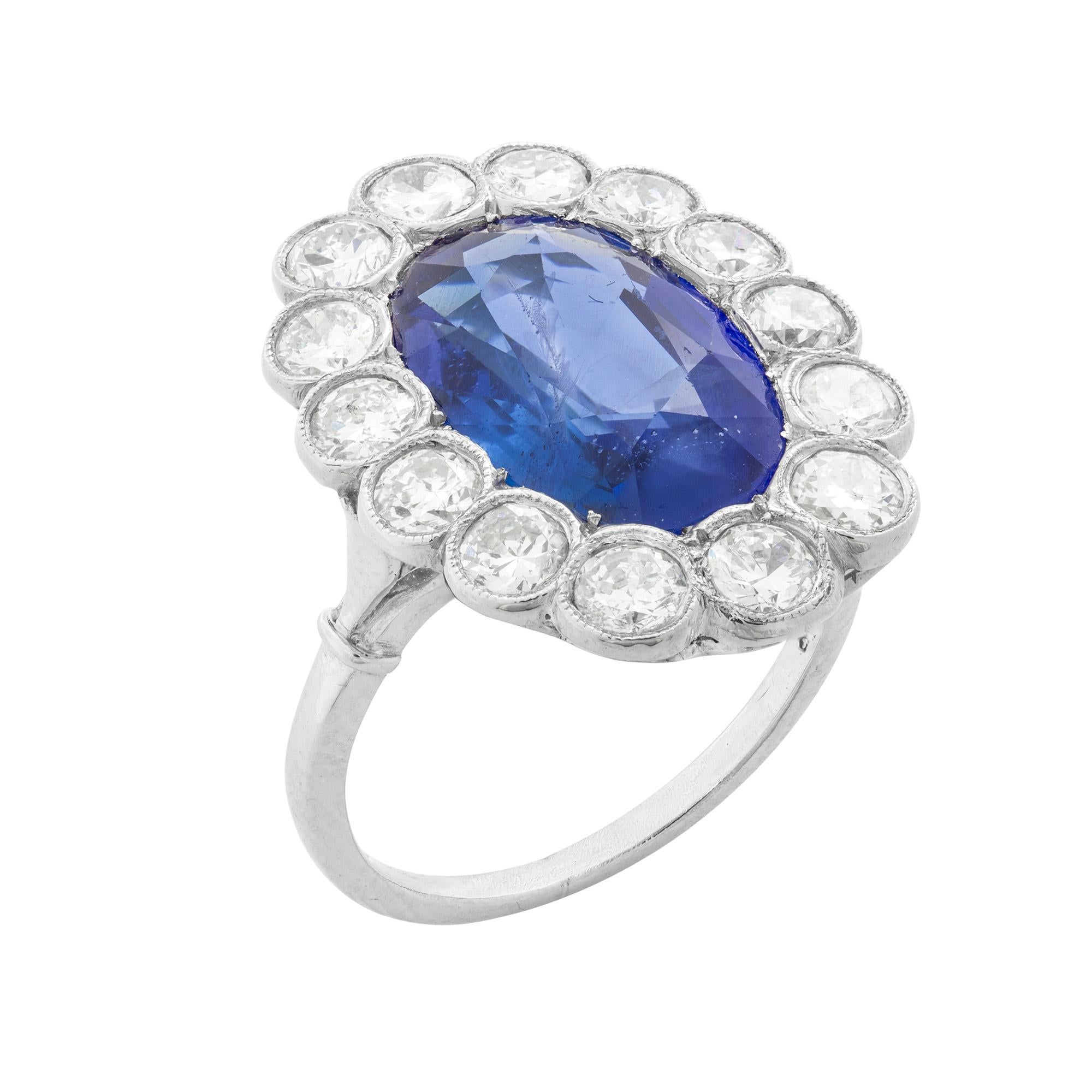 A large sapphire and diamond cluster ring, the oval mixed-cut Burma sapphire weighing a total 5.69 carats surrounded by fourteen round brilliant-cut diamonds weighing a total estimated 1.80 carats mounted in white millegrain settings, the head of