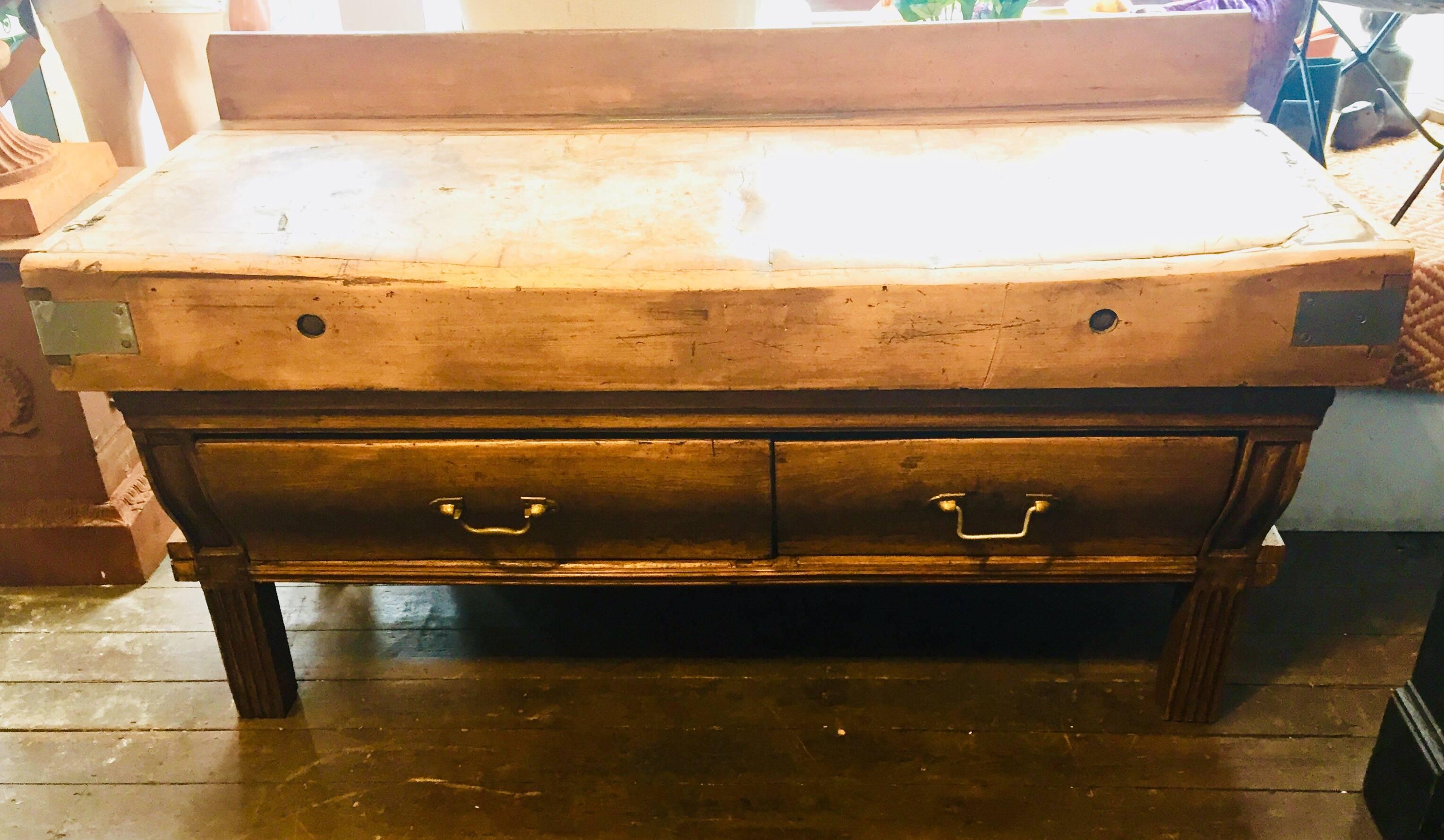 A beautiful and original reclaimed French Boucherie table. Totally sound and solid with good color. Having full-length backboard with a central knife block. A beautifully aged top above two very large drawers with the original brass handles. The