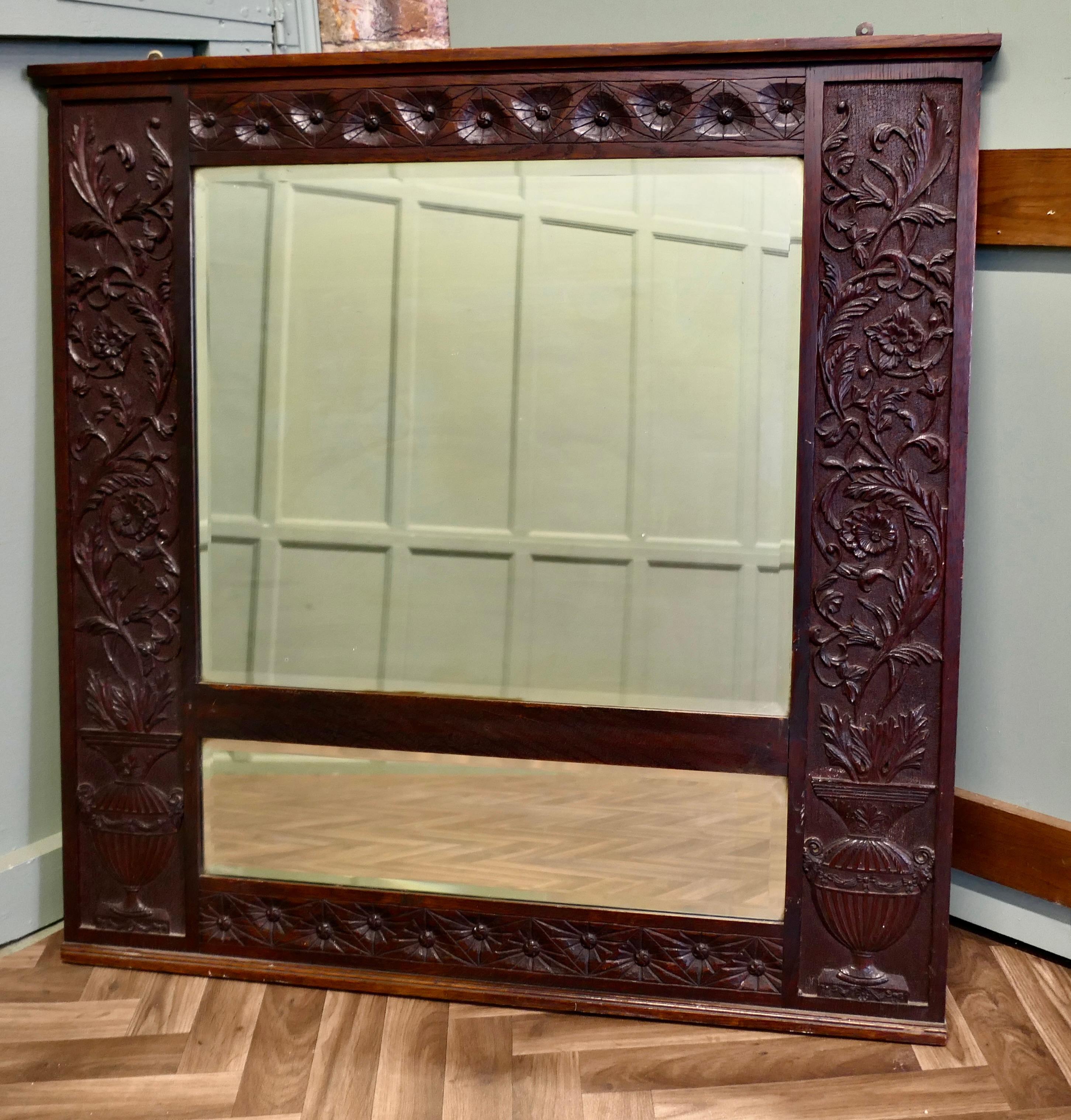 A Large Carved Oak Wall Mirror

The wide Oak Mirror Frame is Beautifully Carved it has deep  flower like roundels along the top and both the sides are carved with a classical urn filled with a tall acanthus arrangement
The mirror has 2 bevelled