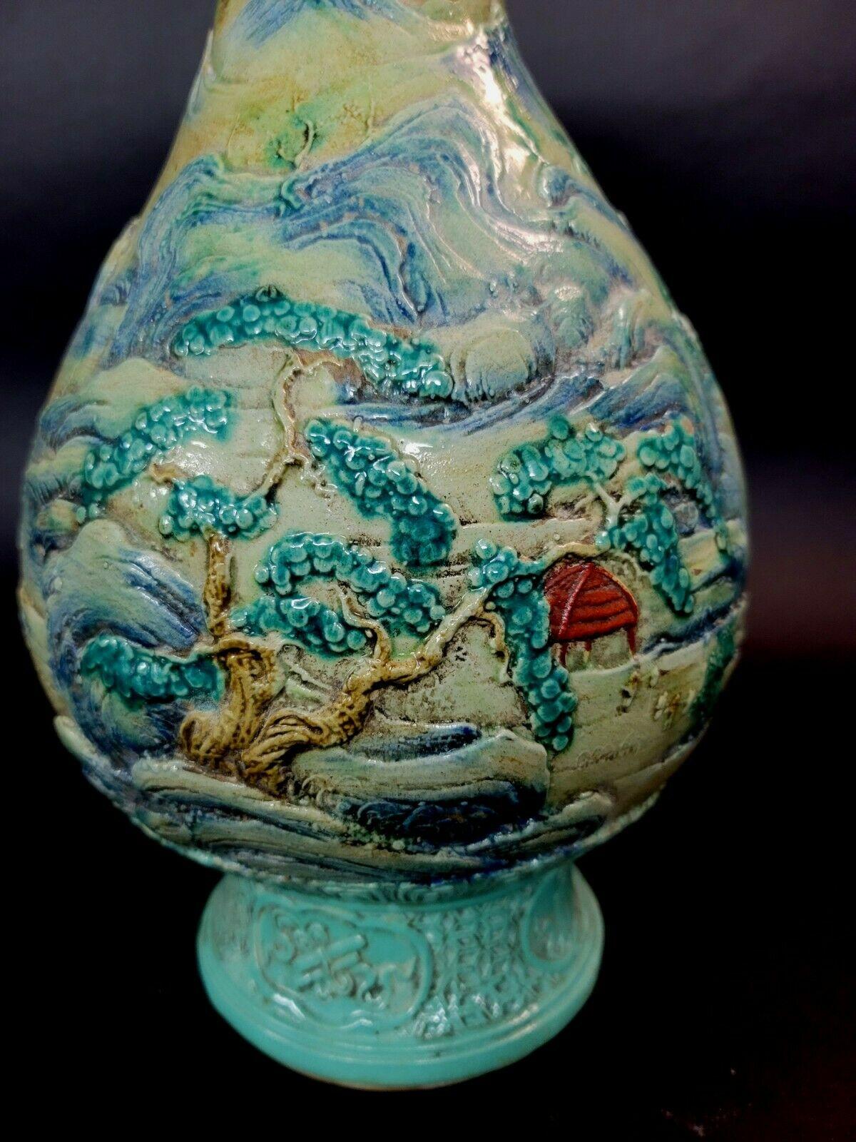 Carved and glazed with a panoramic village scene. A river runs through the village show houses on the riverbanks, fishermen, and mountains in the distance. A red sun is over the horizon. The top and bottom are glazed in turquoise in various borders.